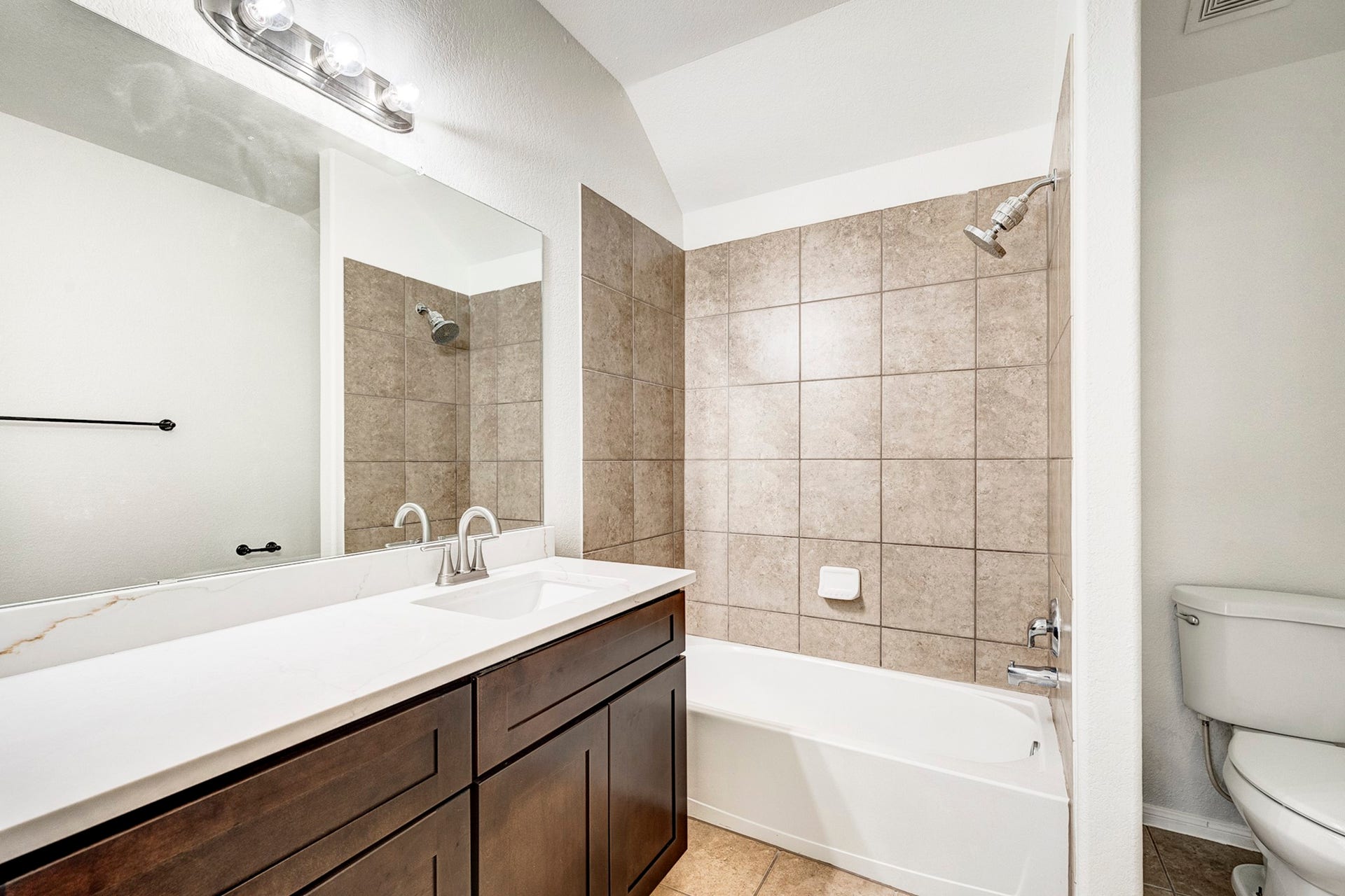 33227 Greenfield Forest Drive, Magnolia, TX 77354 Elegant bathroom featuring a sleek vanity with dual sinks, a tiled shower-tub combo, and modern fixtures for a contemporary feel.