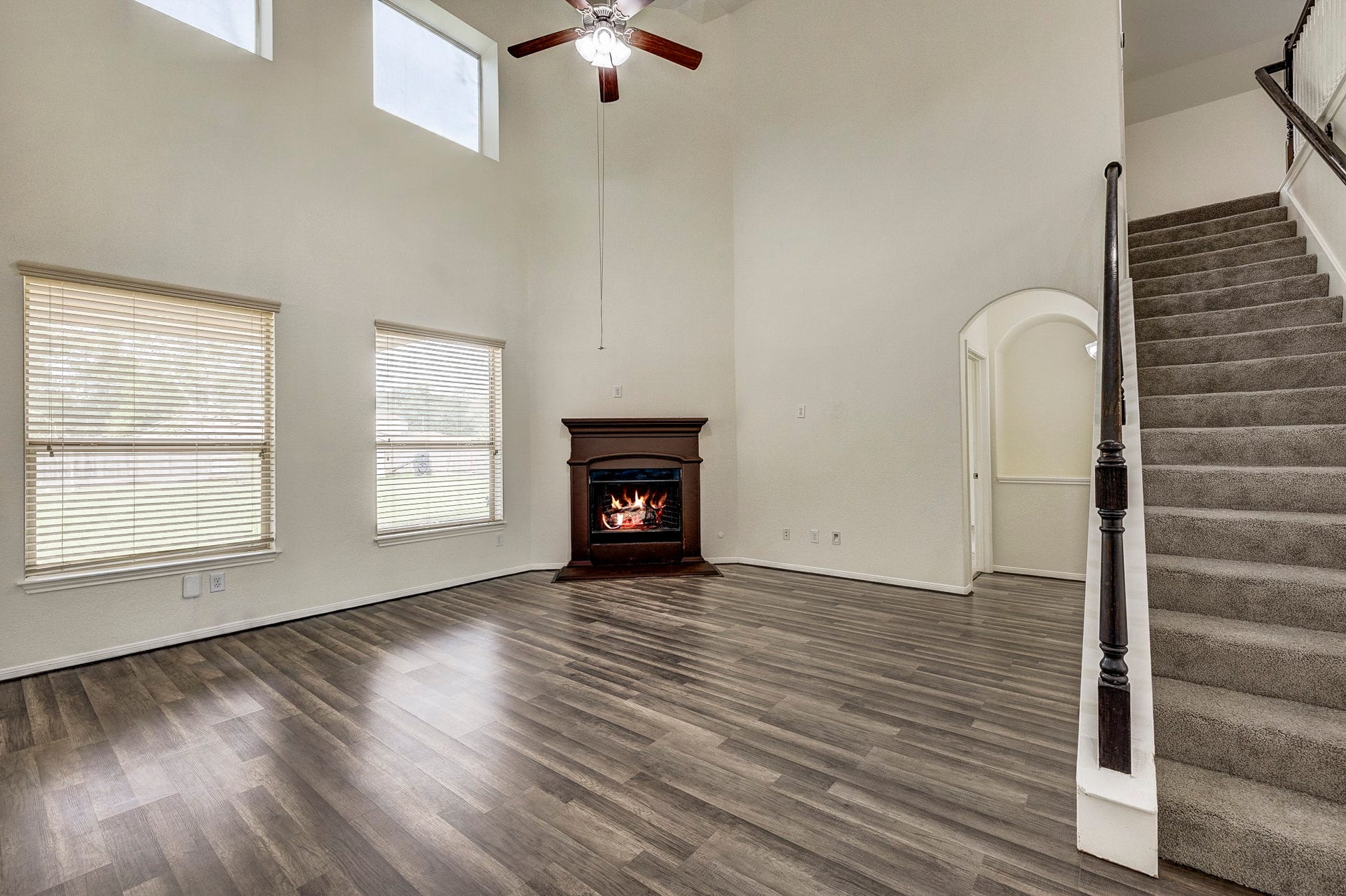 33227 Greenfield Forest Drive, Magnolia, TX 77354 Spacious living area featuring high ceilings, a cozy fireplace, and elegant flooring, complemented by large windows for ample natural light and an open staircase leading to the upper level.