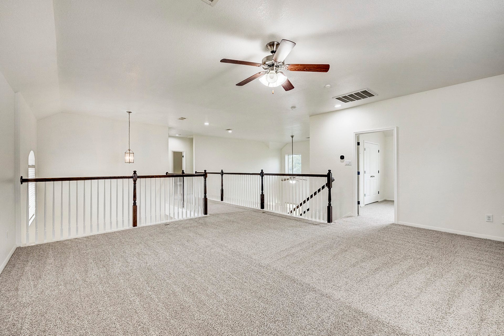 33227 Greenfield Forest Drive, Magnolia, TX 77354 Spacious and bright loft area with plush carpeting, an elegant ceiling fan, and stylish railing overlooking the lower level. Ideal for a cozy lounge or home office setup.