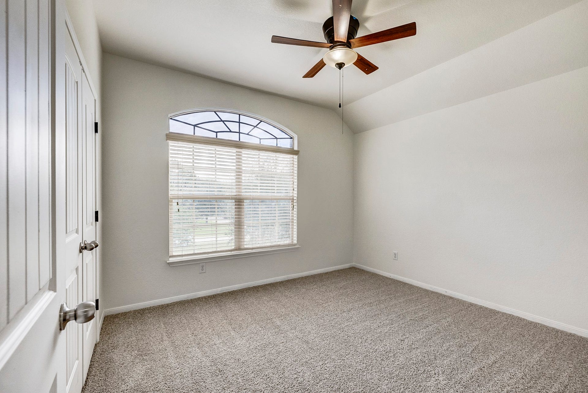 33227 Greenfield Forest Drive, Magnolia, TX 77354 Bright and airy bedroom featuring a large arched window, plush carpeting, and a stylish ceiling fan.