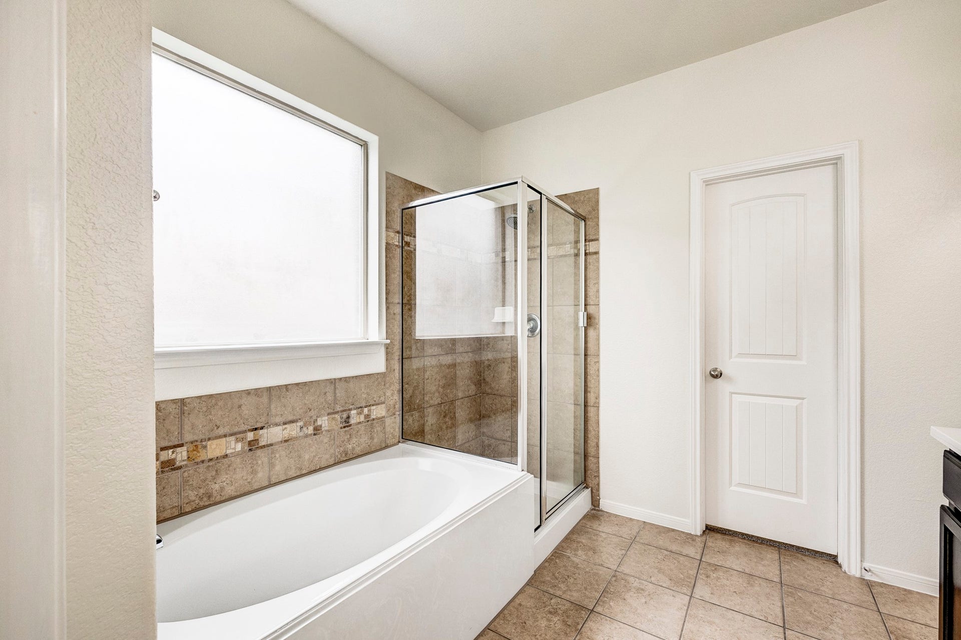 33227 Greenfield Forest Drive, Magnolia, TX 77354 Bright and inviting bathroom featuring a spacious soaking tub, elegant tiled shower, and ample natural light from a large frosted window.