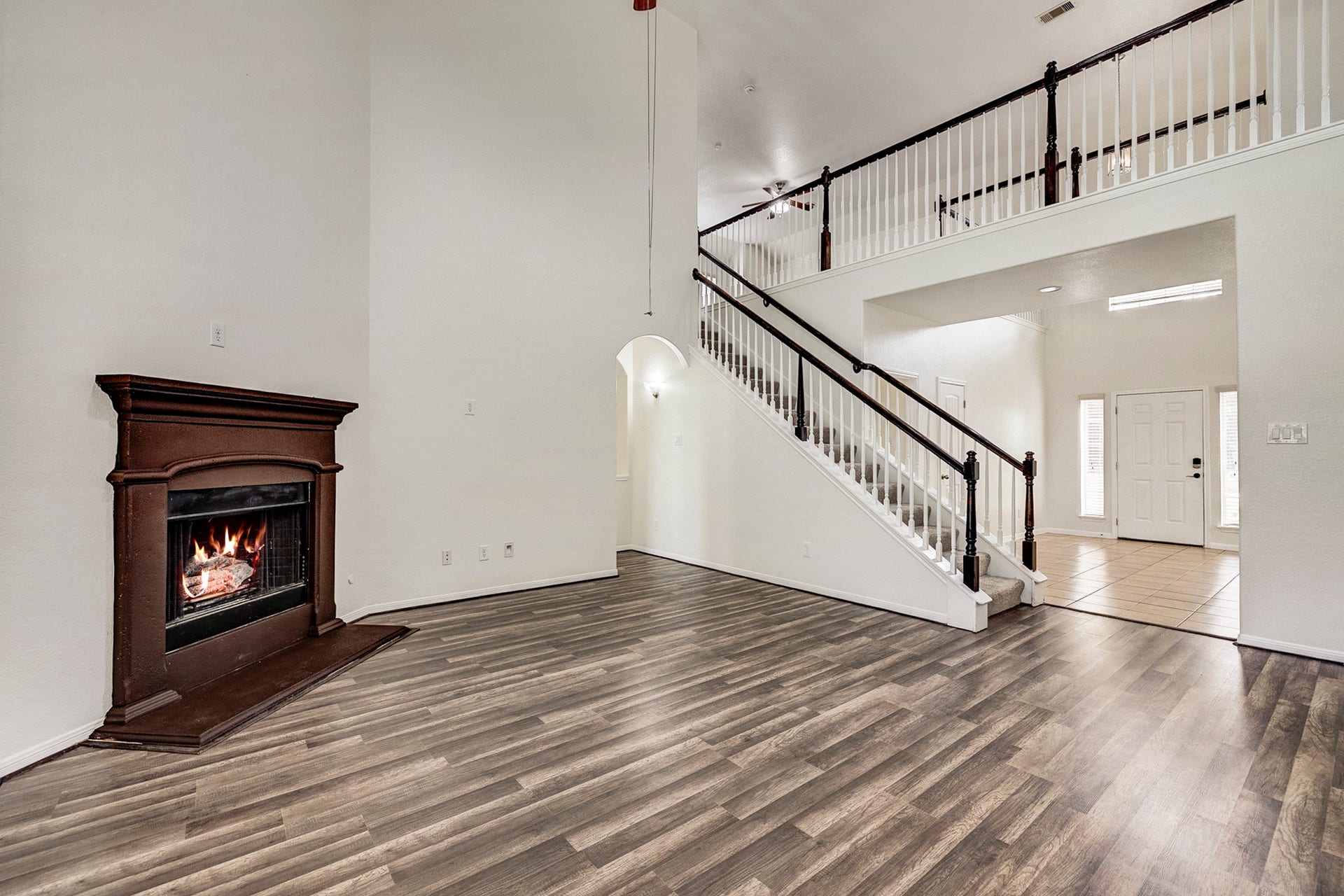 33227 Greenfield Forest Drive, Magnolia, TX 77354 Spacious living area with elegant laminate flooring, a cozy fireplace, and a grand staircase leading to the upper level.