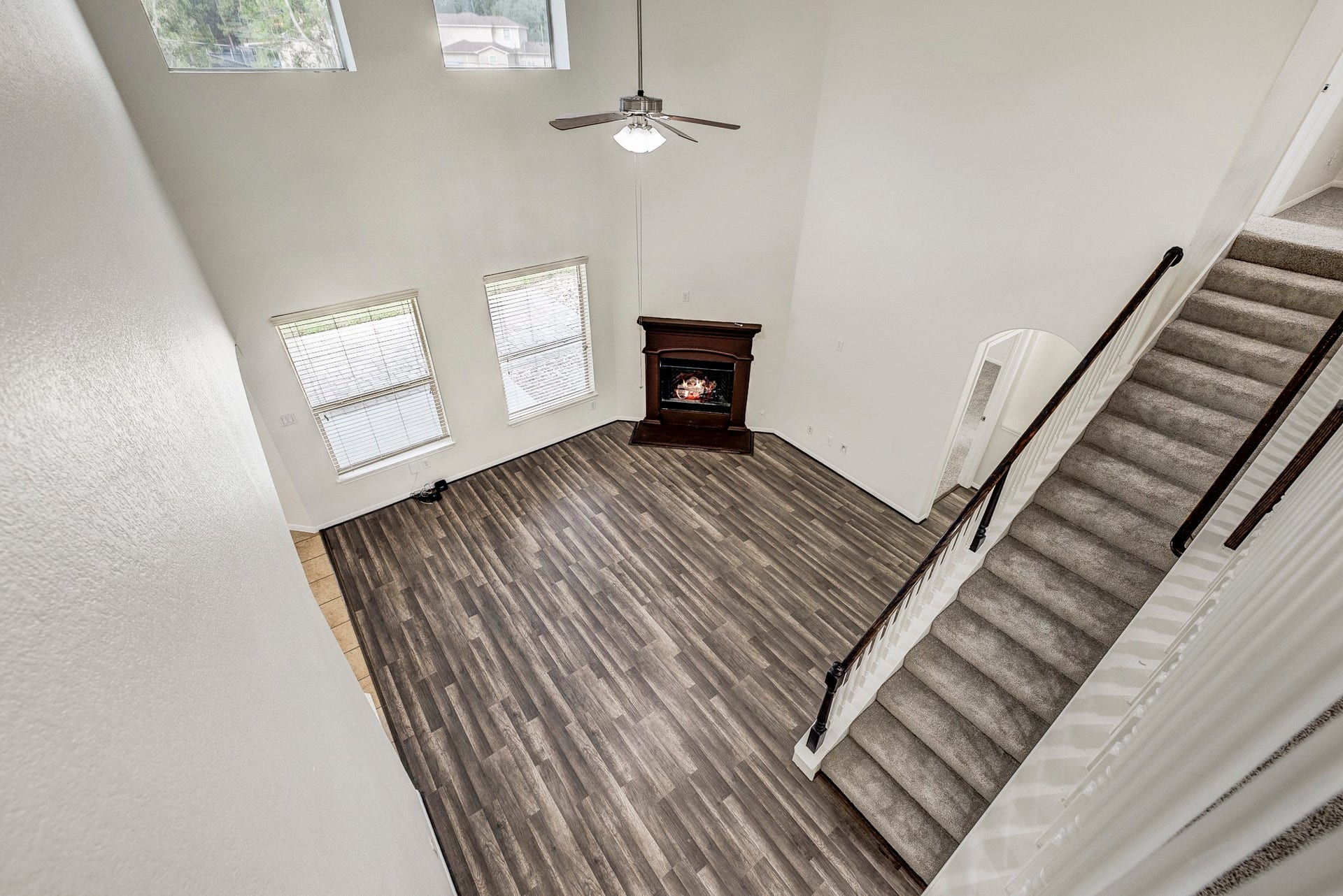 33227 Greenfield Forest Drive, Magnolia, TX 77354 Spacious living room with soaring ceilings, a cozy fireplace, and elegant wood flooring, complemented by abundant natural light from large windows.