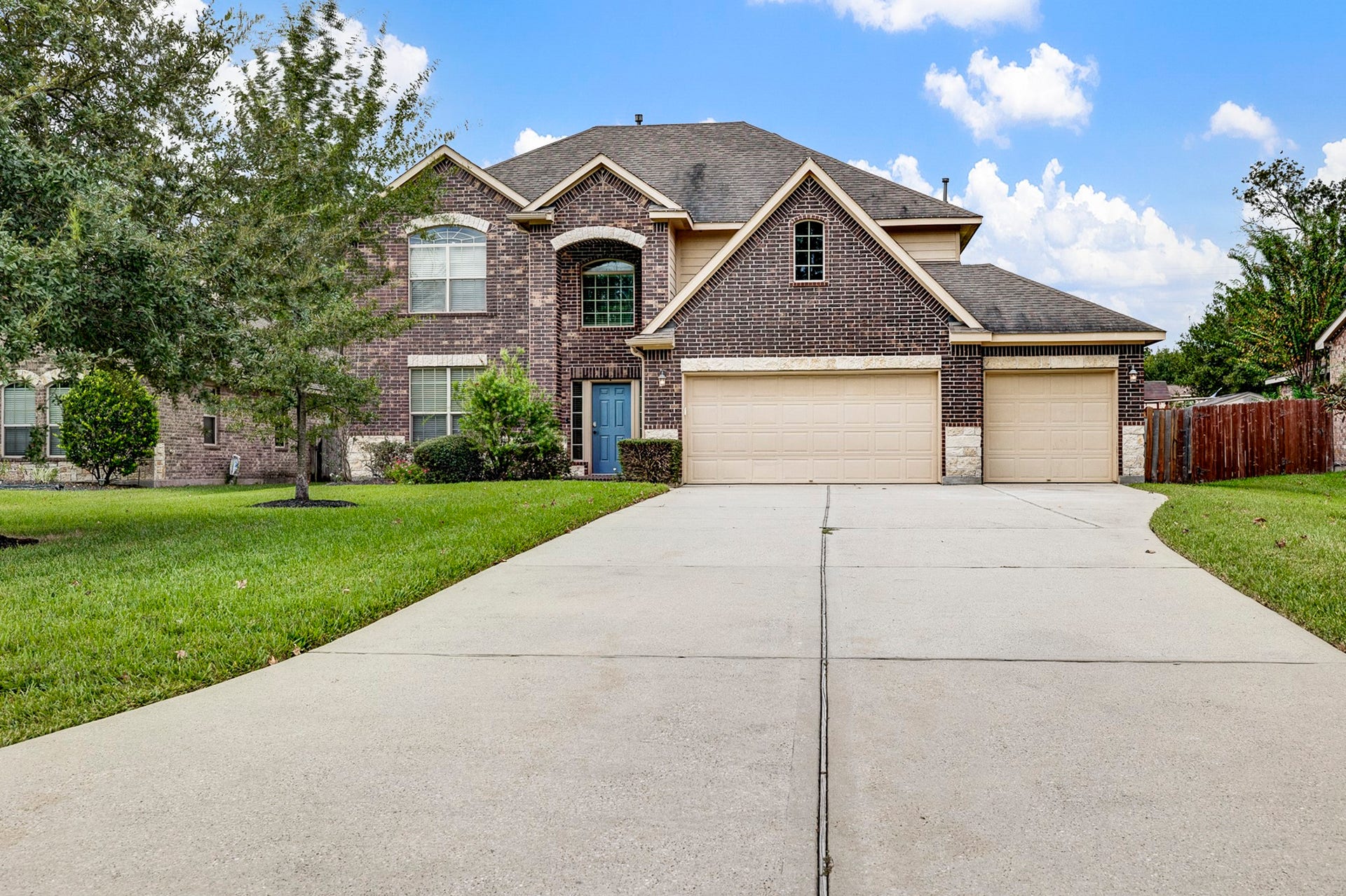 33227 Greenfield Forest Drive, Magnolia, TX 77354 Stunning two-story brick home featuring a spacious three-car garage, manicured lawn, and elegant arched entryway.