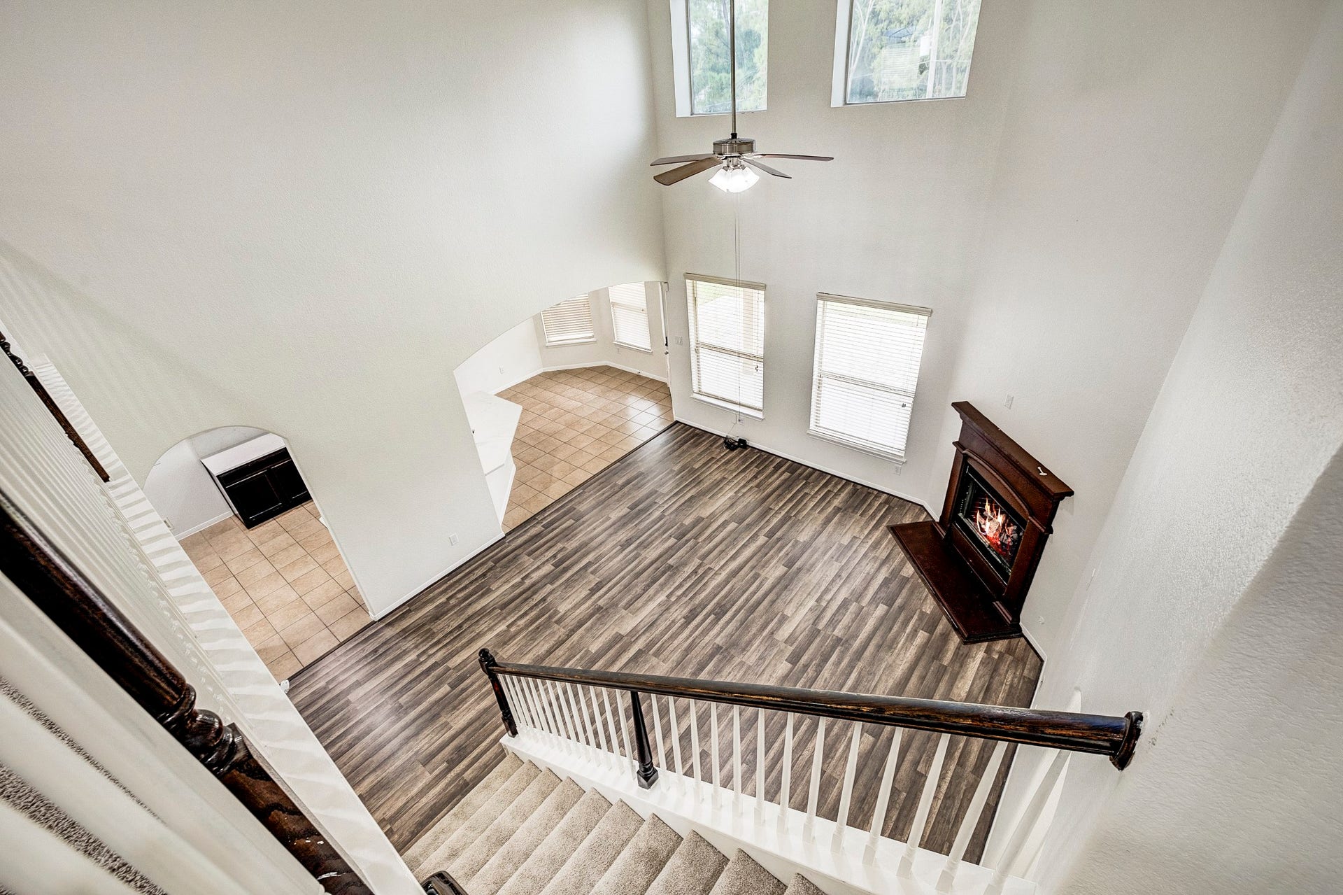 33227 Greenfield Forest Drive, Magnolia, TX 77354 Spacious living area with soaring ceilings, abundant natural light from large windows, elegant wood flooring, and a cozy corner fireplace for ultimate comfort.