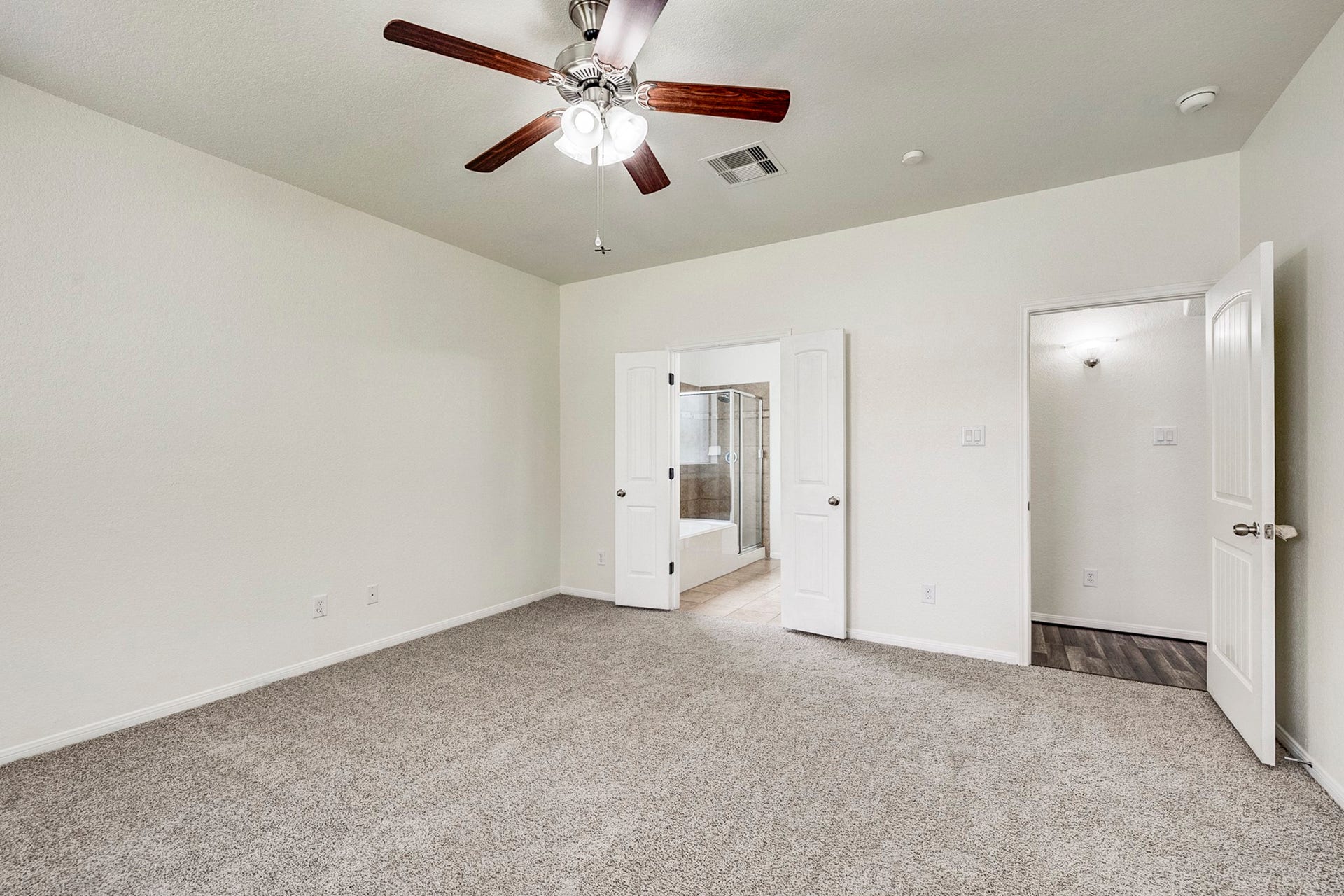 33227 Greenfield Forest Drive, Magnolia, TX 77354 Spacious bedroom featuring plush carpeting, a ceiling fan, and direct access to a modern bathroom with double doors.