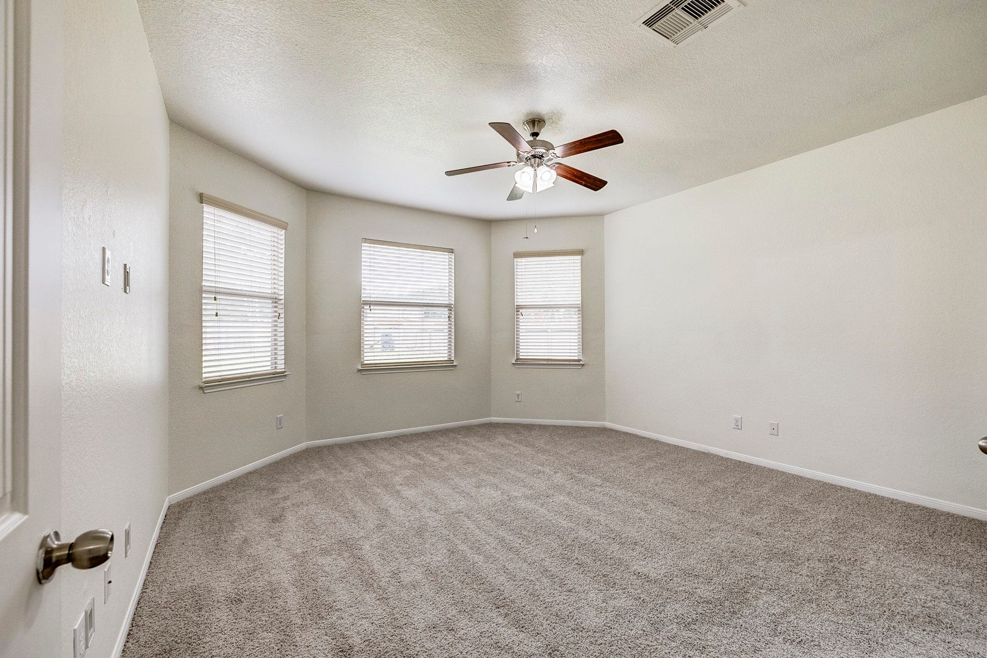 33227 Greenfield Forest Drive, Magnolia, TX 77354 Spacious bedroom featuring neutral-toned carpet, three large windows for natural light, and a modern ceiling fan.