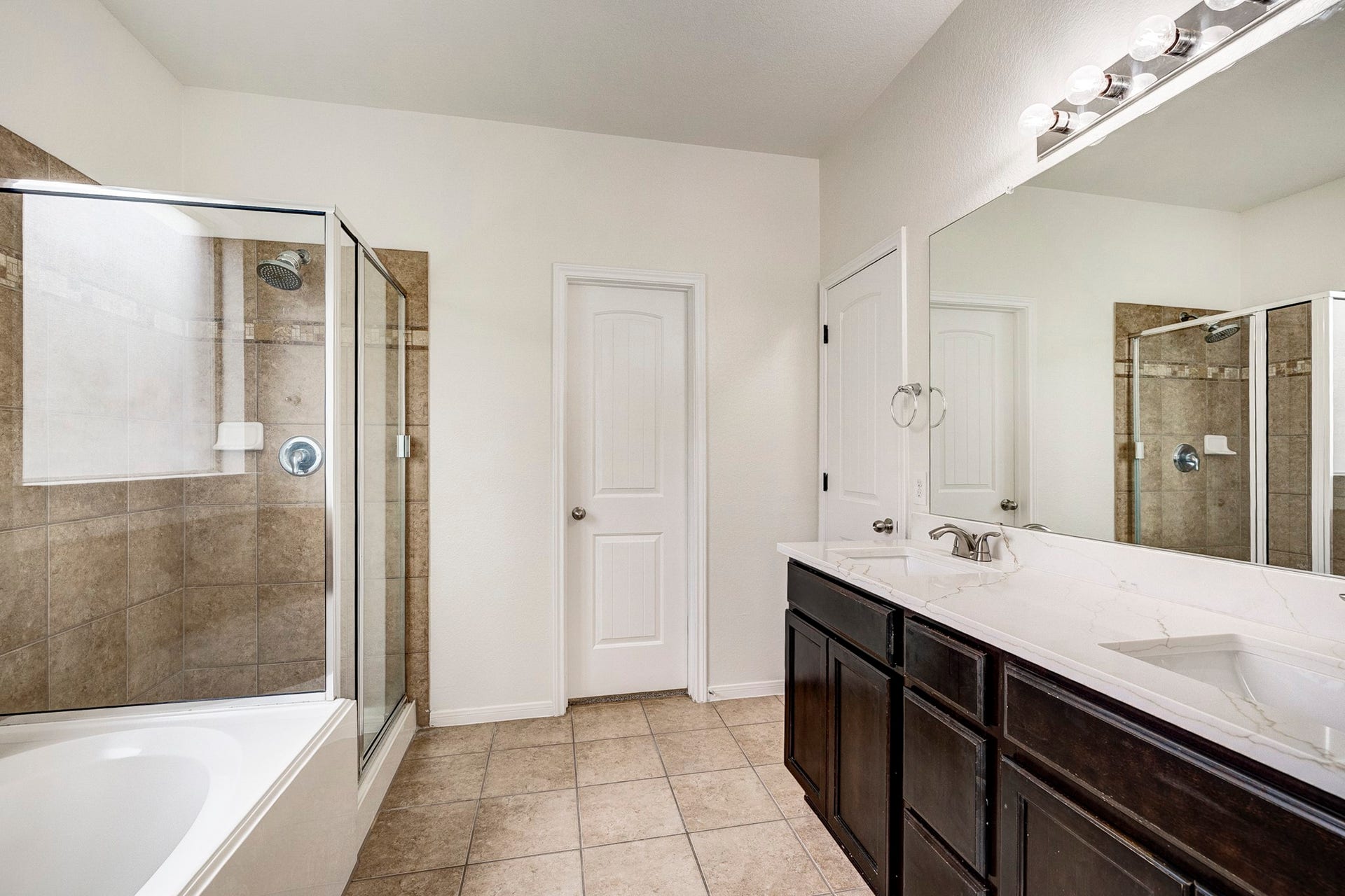 33227 Greenfield Forest Drive, Magnolia, TX 77354 Spacious bathroom featuring a sleek glass-enclosed shower, a luxurious soaking tub, and a modern double vanity with elegant dark cabinetry.