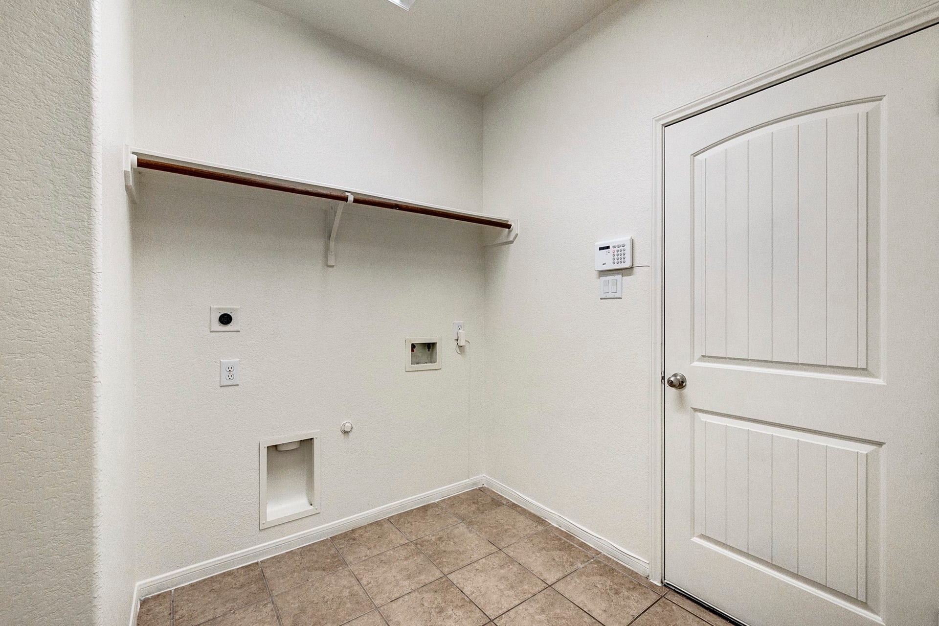 33227 Greenfield Forest Drive, Magnolia, TX 77354 Spacious laundry room with tile flooring, washer and dryer hookups, a convenient shelf for storage, and a secure entry door.