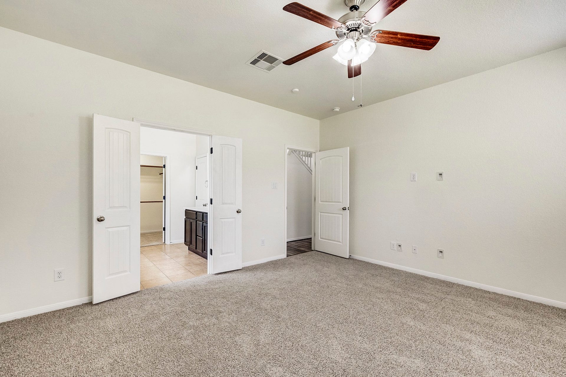 33227 Greenfield Forest Drive, Magnolia, TX 77354 Spacious bedroom with plush carpeting, a ceiling fan, and double doors leading to an en-suite bathroom.