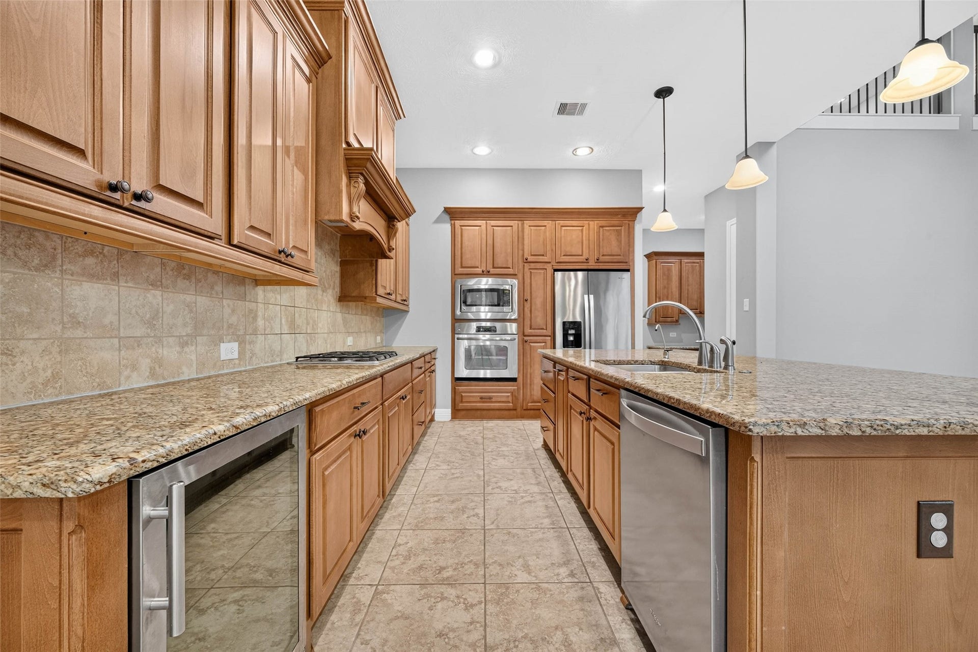 4419 Montcliff Bend Court, Sugar Land, TX 77479 This modern kitchen features an expansive center island with a built-in sink, stainless steel appliances, and a dedicated wine refrigerator