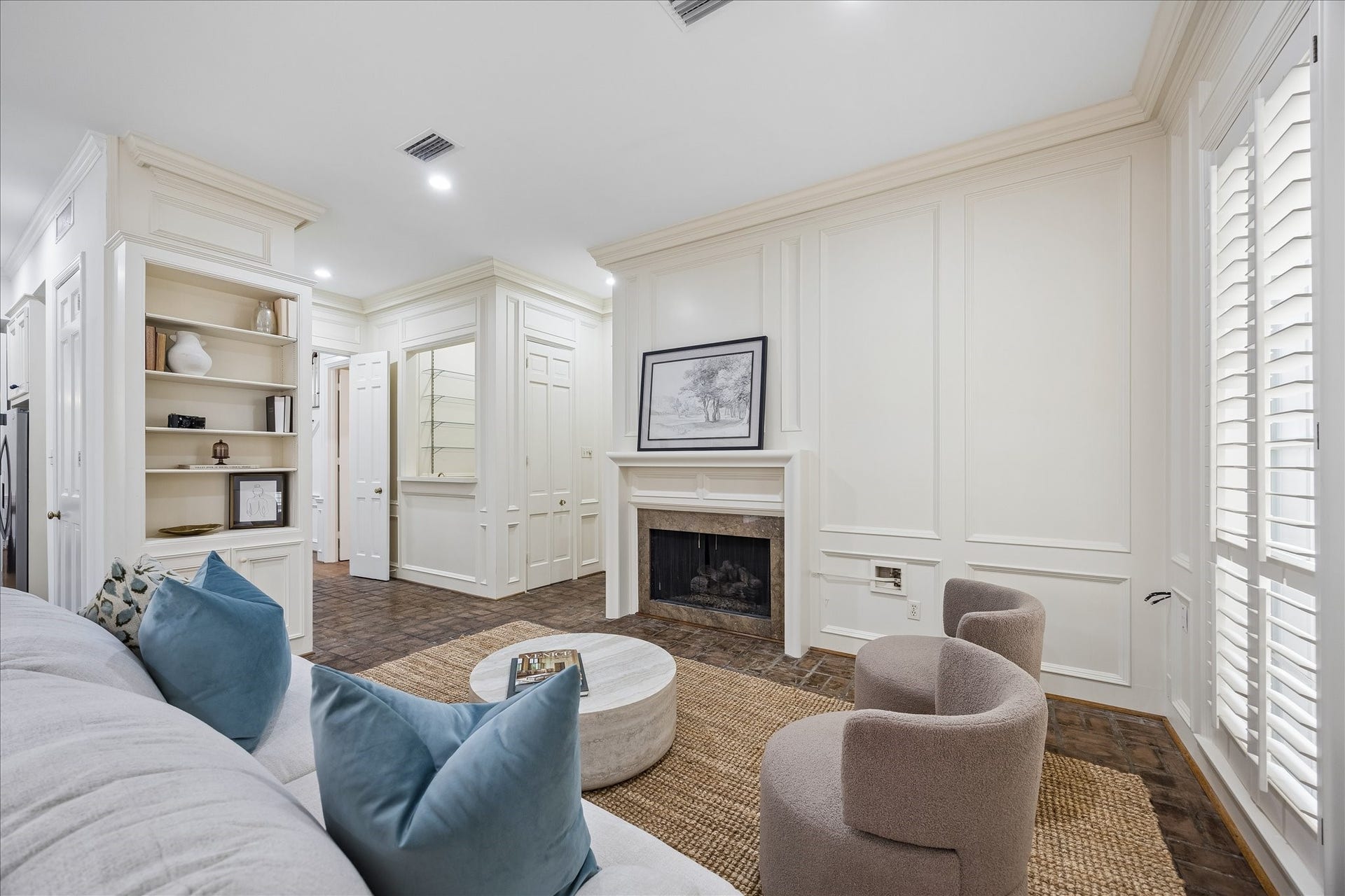 1422 Nantucket Drive, #C, Houston, TX 77057 Family room with gas-log fireplace, custom millwork, built-in shelving and adjacent wet bar with sink and beverage refrigerator.