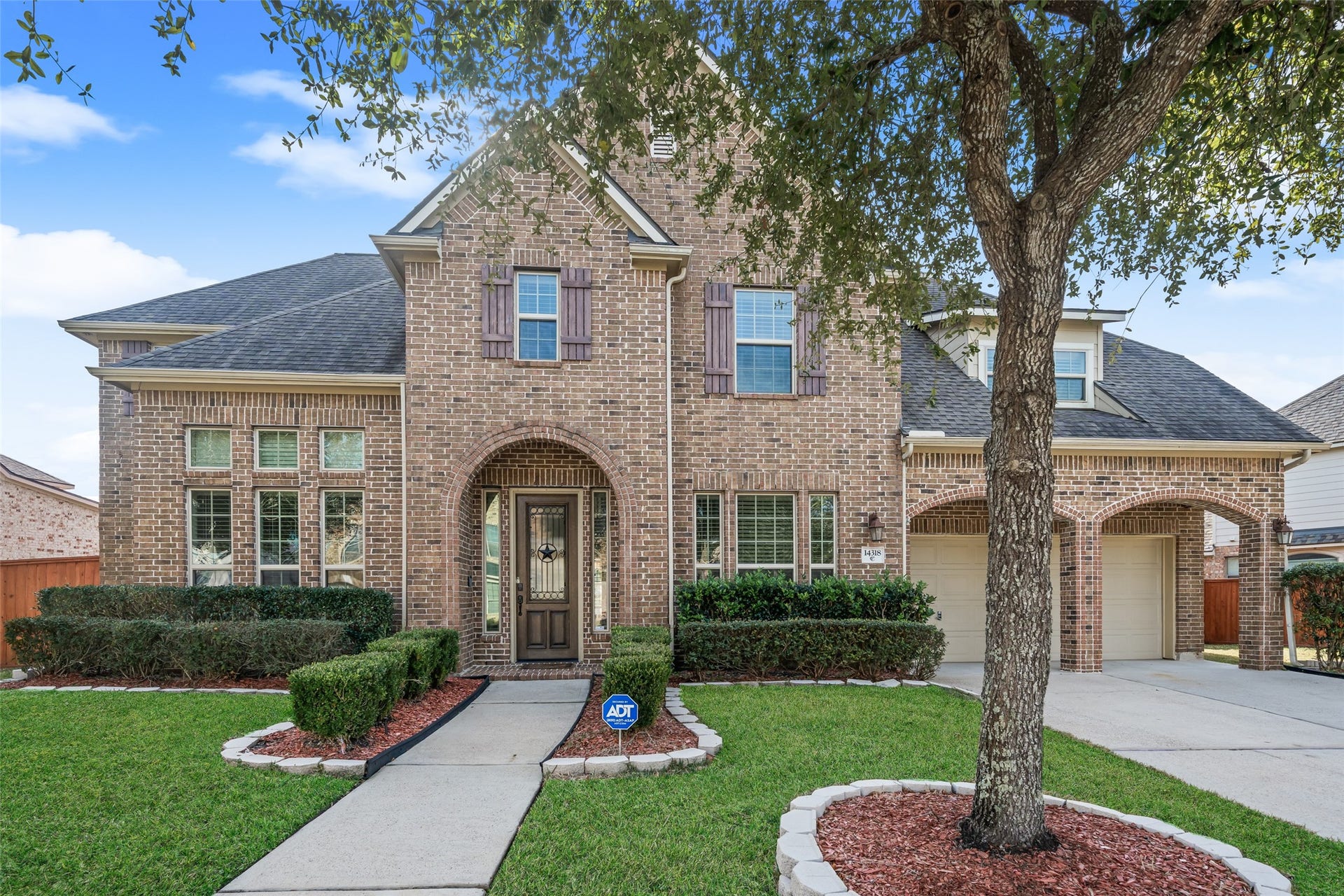 14318 Red Creek Cove Lane, Humble, TX 77396 Welcoming arched entryway, manicured front lawn. Elegant windows and a mature tree add to its curb appeal, making it a perfect family residence.