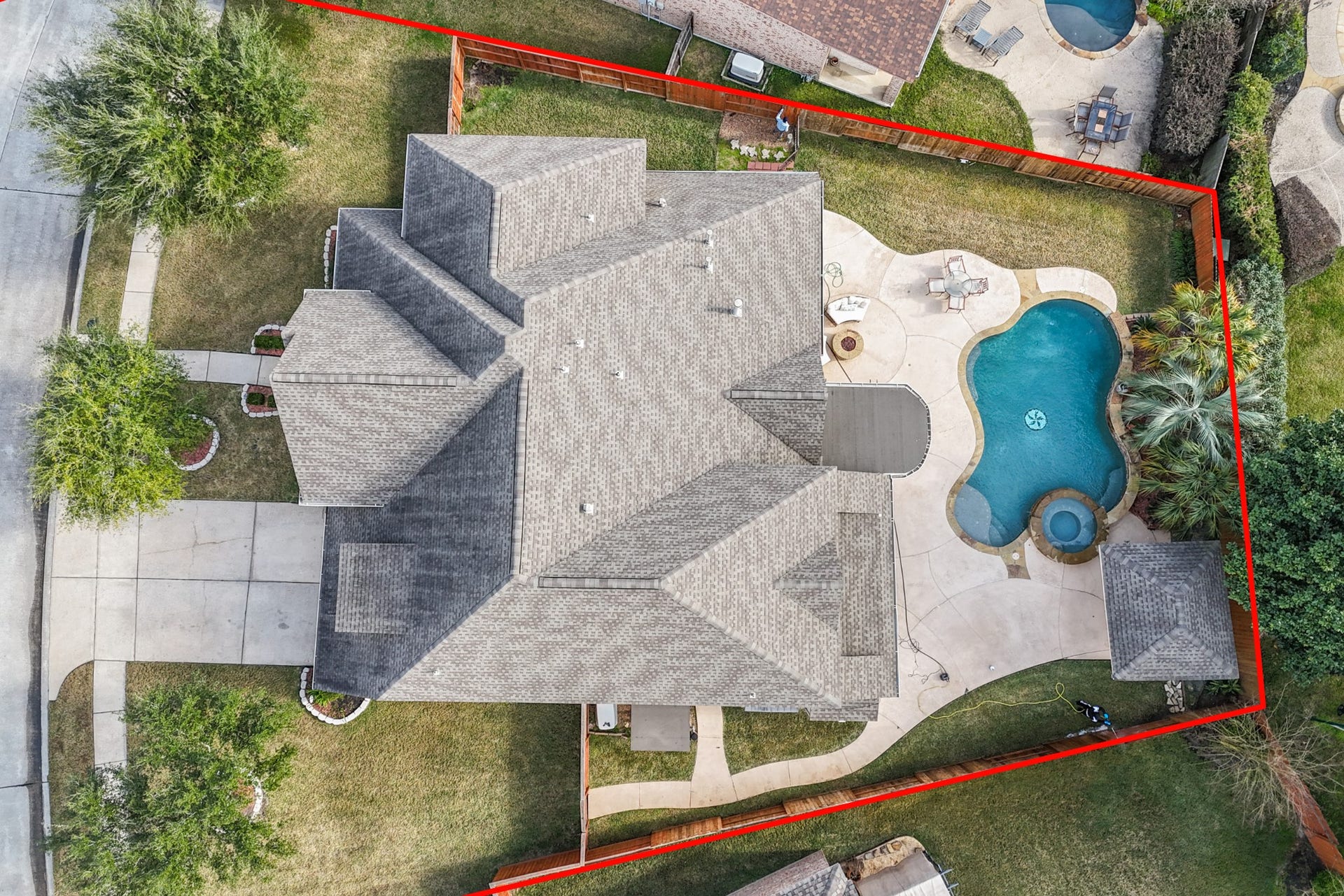 14318 Red Creek Cove Lane, Humble, TX 77396 This aerial view showcases a spacious home with newer roof, a large driveway, and a beautifully landscaped yard. The backyard features a luxurious pool with a spa, surrounded by a patio and a privacy fence, perfect for outdoor entertaining.