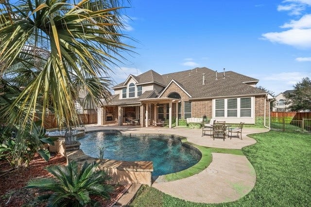 14318 Red Creek Cove Lane, Humble, TX 77396 This photo showcases a spacious backyard with a well-maintained pool, patio, and seating area. There is also a gated dog run on the side.