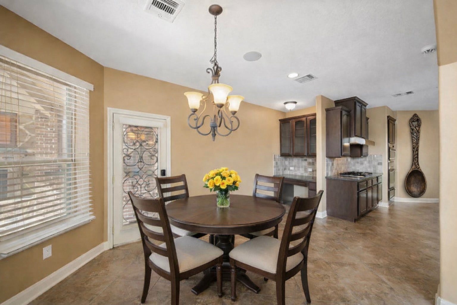 14318 Red Creek Cove Lane, Humble, TX 77396 Breakfast area is adjacent to a kitchen. Natural light pours in through large windows, and a decorative chandelier adds elegance. The space is warm and inviting, perfect for family meals.