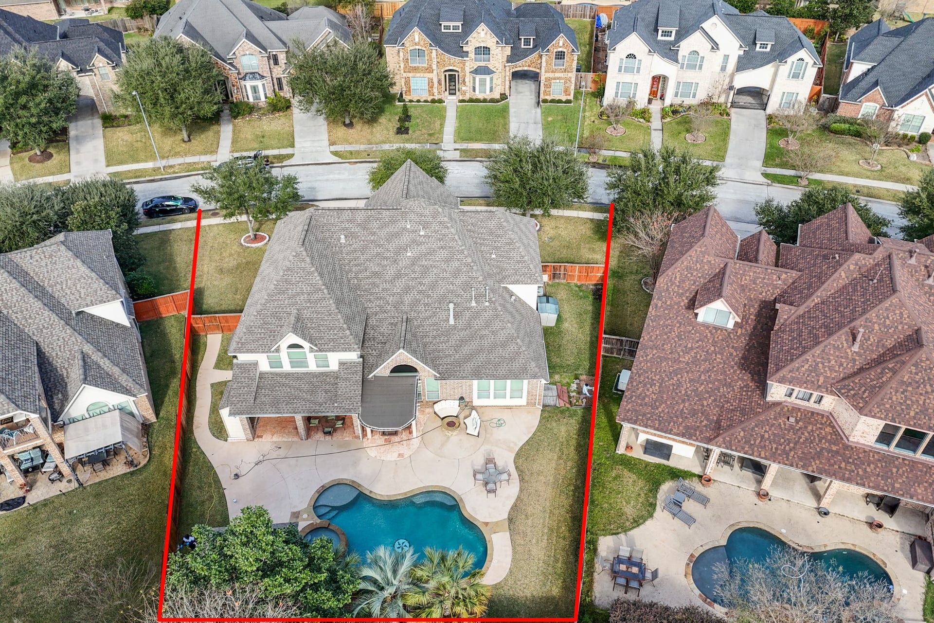 14318 Red Creek Cove Lane, Humble, TX 77396 Aerial view showcases the neatly landscaped yard, featuring a large swimming pool and patio area. The property is outlined in red and is situated in a suburban neighborhood with similar homes nearby.