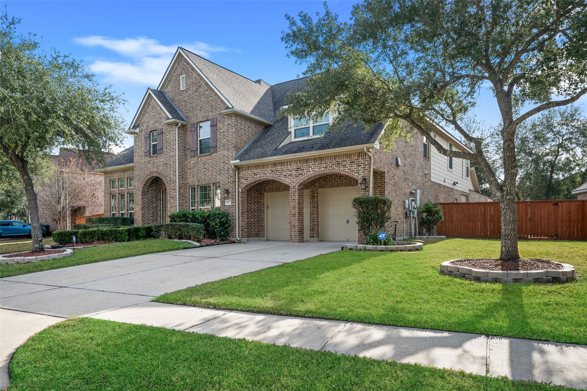 14318 Red Creek Cove Lane, Humble, TX 77396 Two-story brick home with a neatly manicured lawn, mature trees, and a spacious driveway leading to a 3-car tandem garage.