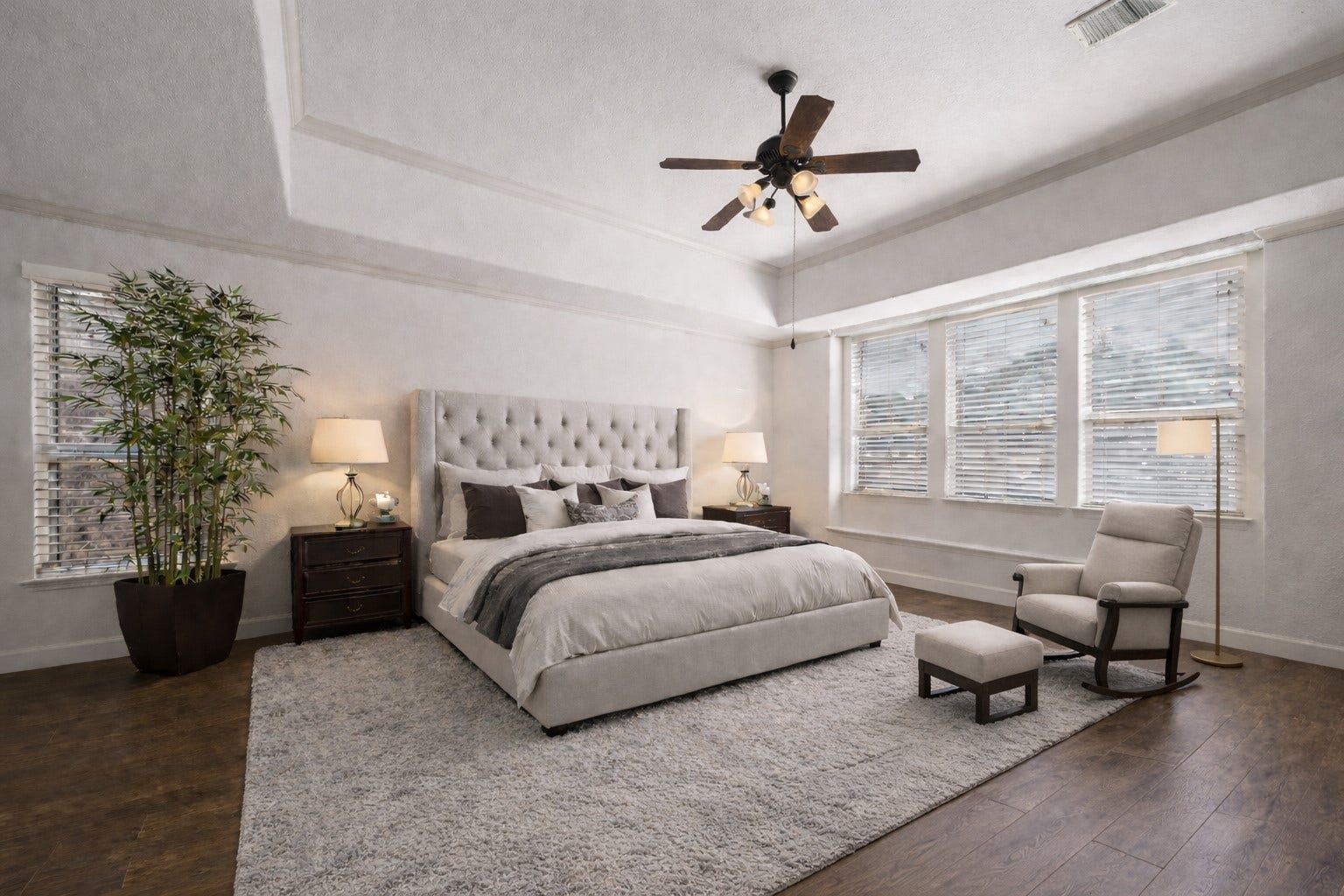 14318 Red Creek Cove Lane, Humble, TX 77396 Spacious primary bedroom features abundant natural light from large windows. The warm wood flooring creates a serene and inviting atmosphere.
