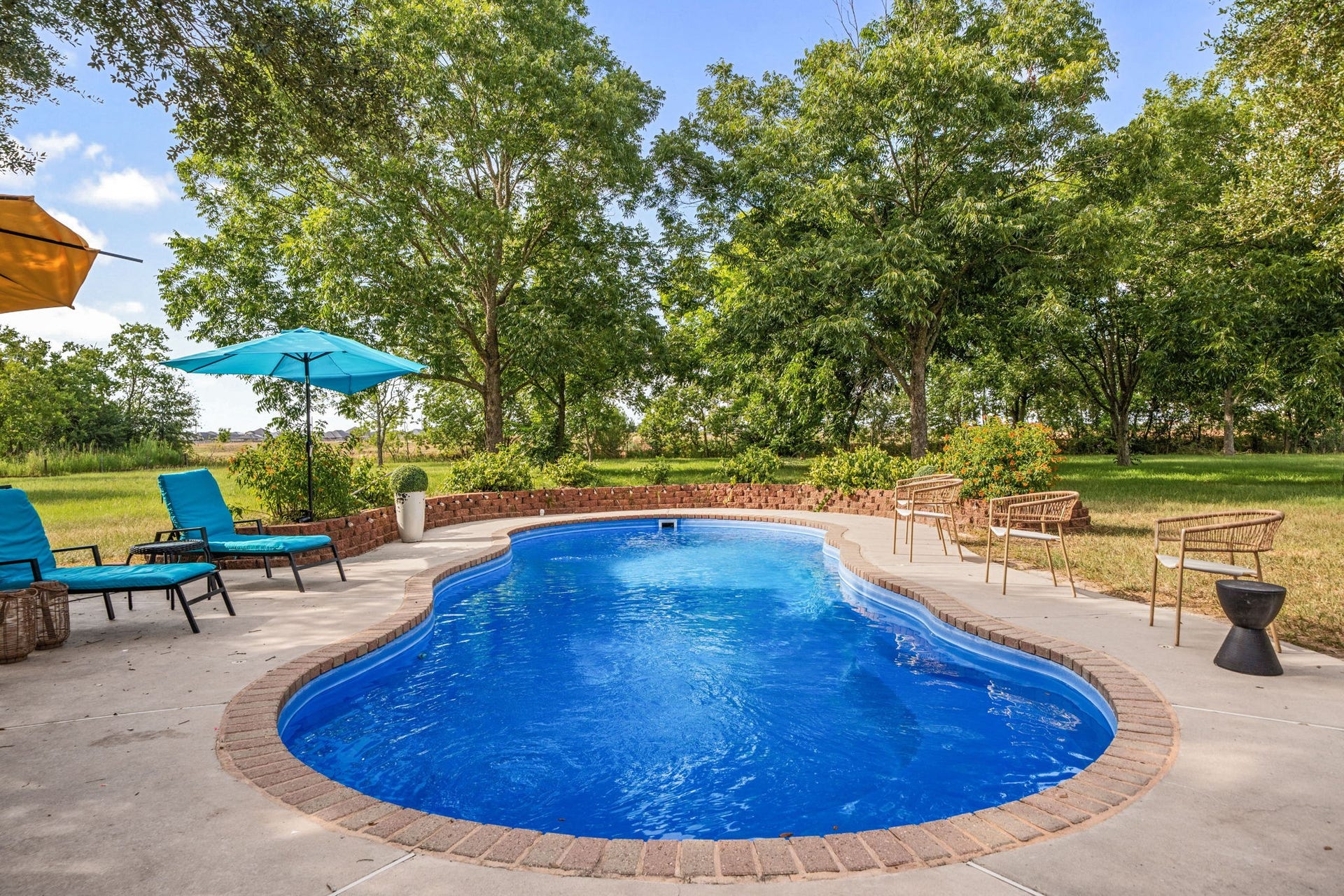 28310 Rose Lane, Katy, TX 77494 Private backyard oasis highlighting a sparkling, custom-shaped in-ground swimming pool finished with a classic brick-paved border. An expansive concrete patio surround provides plenty of layout options for soaking up the sun or relaxing in the shade. Framed by a lush green lawn and majestic mature trees, this tranquil outdoor retreat offers exceptional privacy for everyday living and weekend entertaining.
