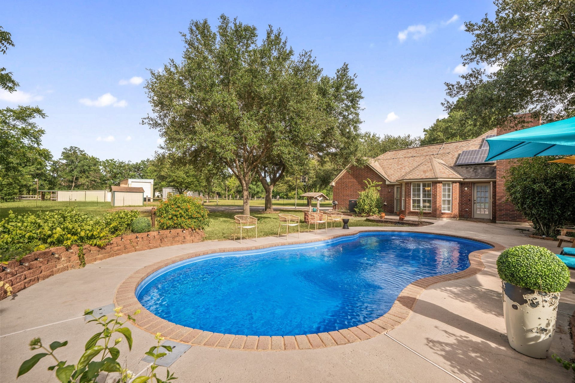 28310 Rose Lane, Katy, TX 77494 A spacious concrete pool deck offers ample room for sunbathing and outdoor gatherings, all framed by a meticulously manicured lawn and mature privacy trees. The property showcases an expansive, open lot layout that leads directly to the charming brick home structure, seamlessly connecting indoor comfort with outdoor entertaining.