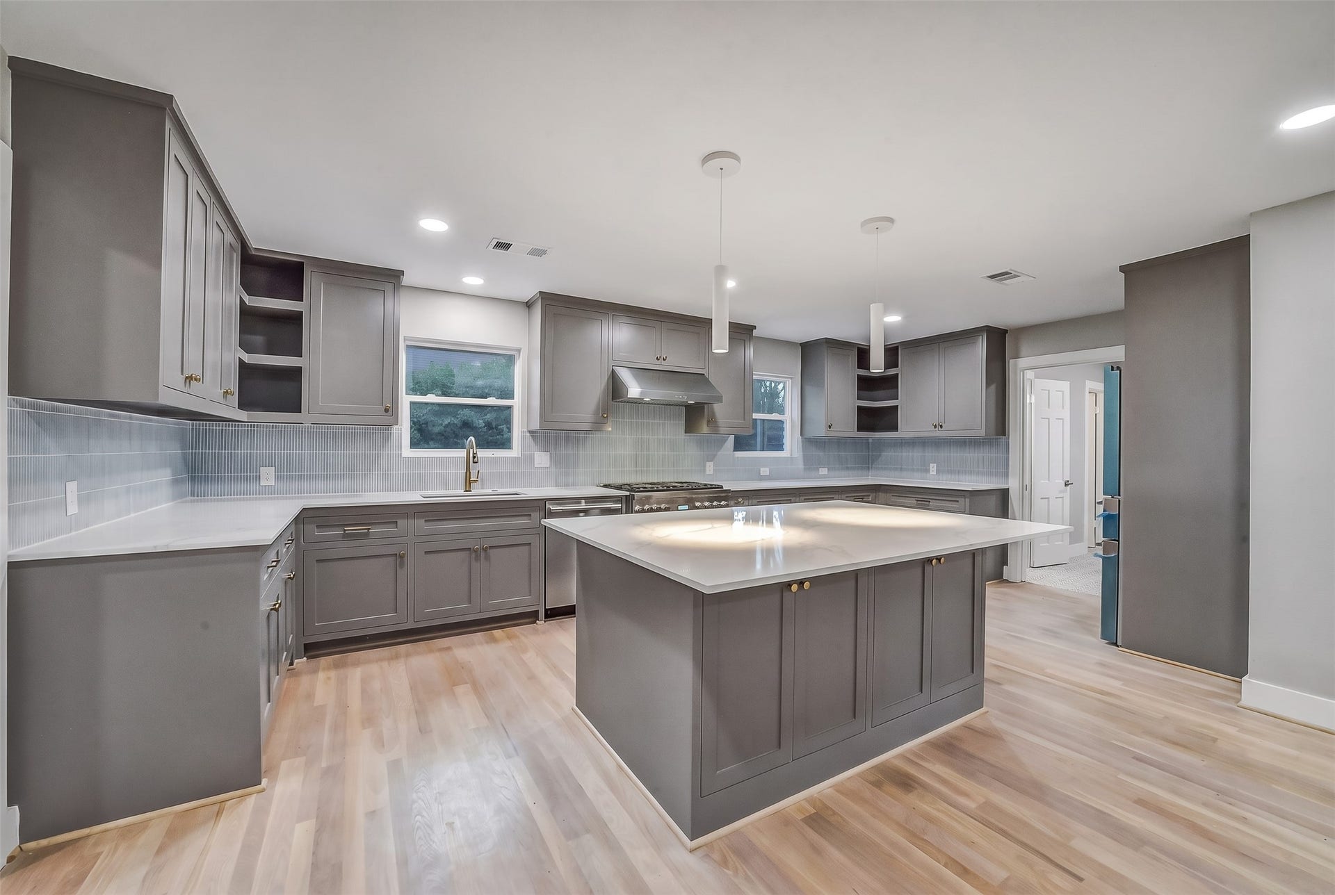 5318 Queensloch Drive, Houston, TX 77096 A modern, welcoming kitchen flows seamlessly into an open living and dining area, creating one spacious, connected environment. A large central island with comfortable seating, sleek cabinetry, generous countertops, and warm, understated finishes.