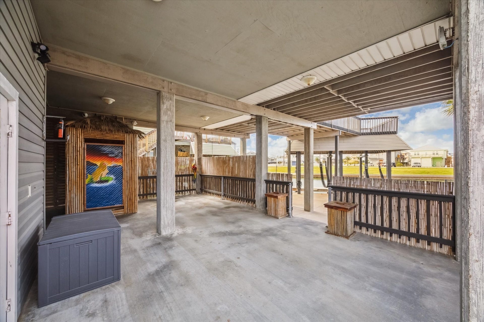 519 Westerly Drive, Tiki Island, TX 77554 Spacious covered patio area with concrete flooring, ideal for outdoor gatherings. It features a unique tiki-style structure 9 your ground level 1/2 bath) . The patio overlooks the pool creating a relaxed, tropical atmosphere.