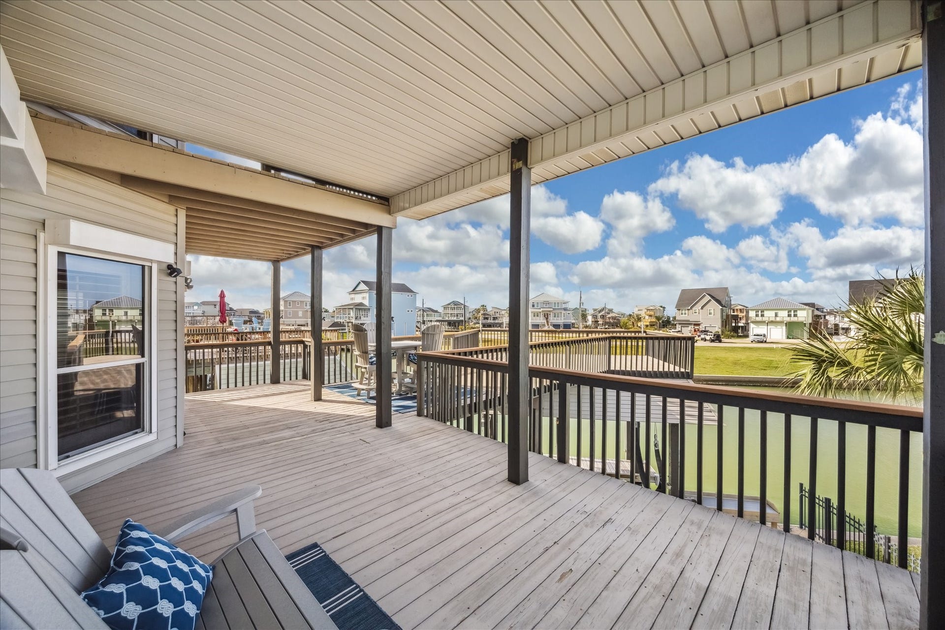 519 Westerly Drive, Tiki Island, TX 77554 A spacious, covered deck overlooking a serene waterfront with views of neighboring homes. Ideal for relaxing and enjoying the outdoors.