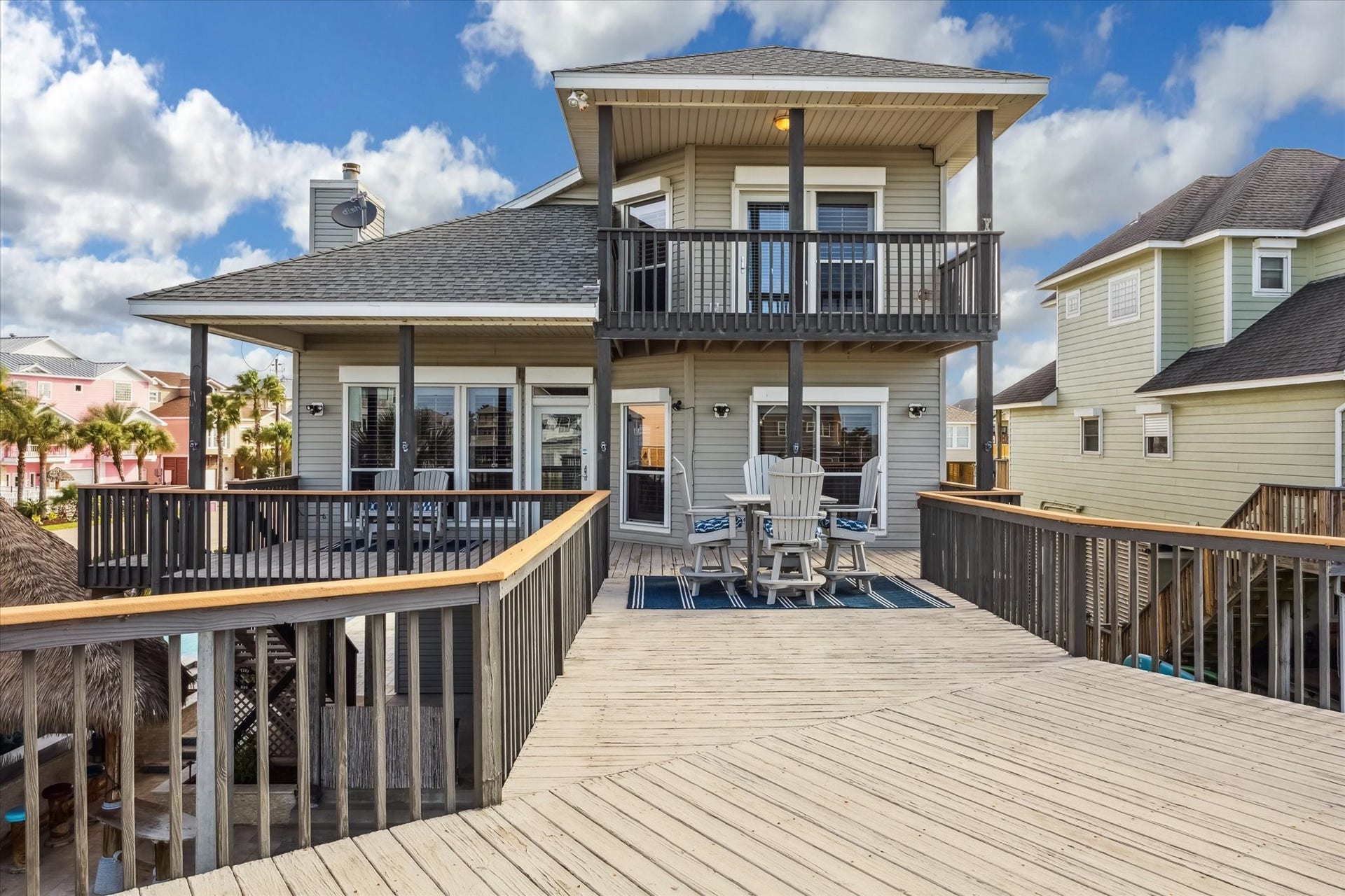519 Westerly Drive, Tiki Island, TX 77554 This inviting home features a spacious wooden deck with ample seating, perfect for entertaining. The exterior offers a modern design with a two-story layout and a charming balcony. Ideal for enjoying sunny days.