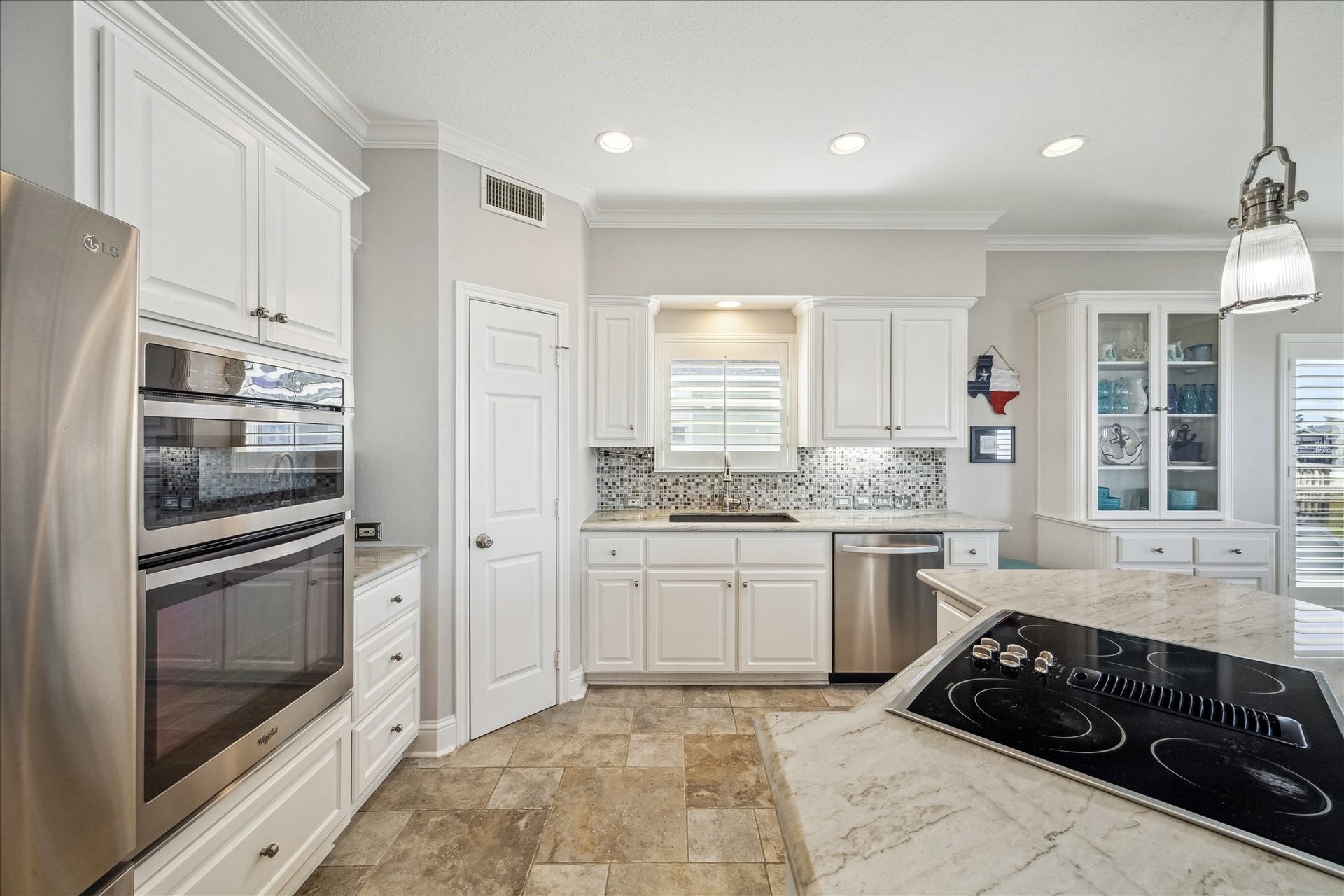 519 Westerly Drive, Tiki Island, TX 77554 This kitchen features a built-in oven, a sleek cooktop on a marble island, and ample natural light.