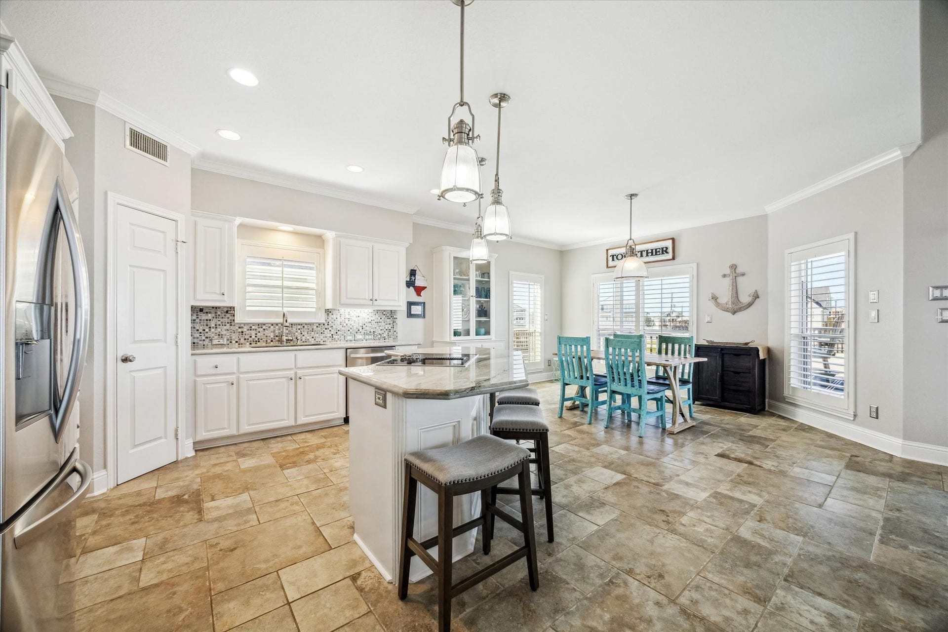 519 Westerly Drive, Tiki Island, TX 77554 This spacious kitchen and dining area features modern appliances, an island with seating, and ample natural light. The space boasts a coastal vibe