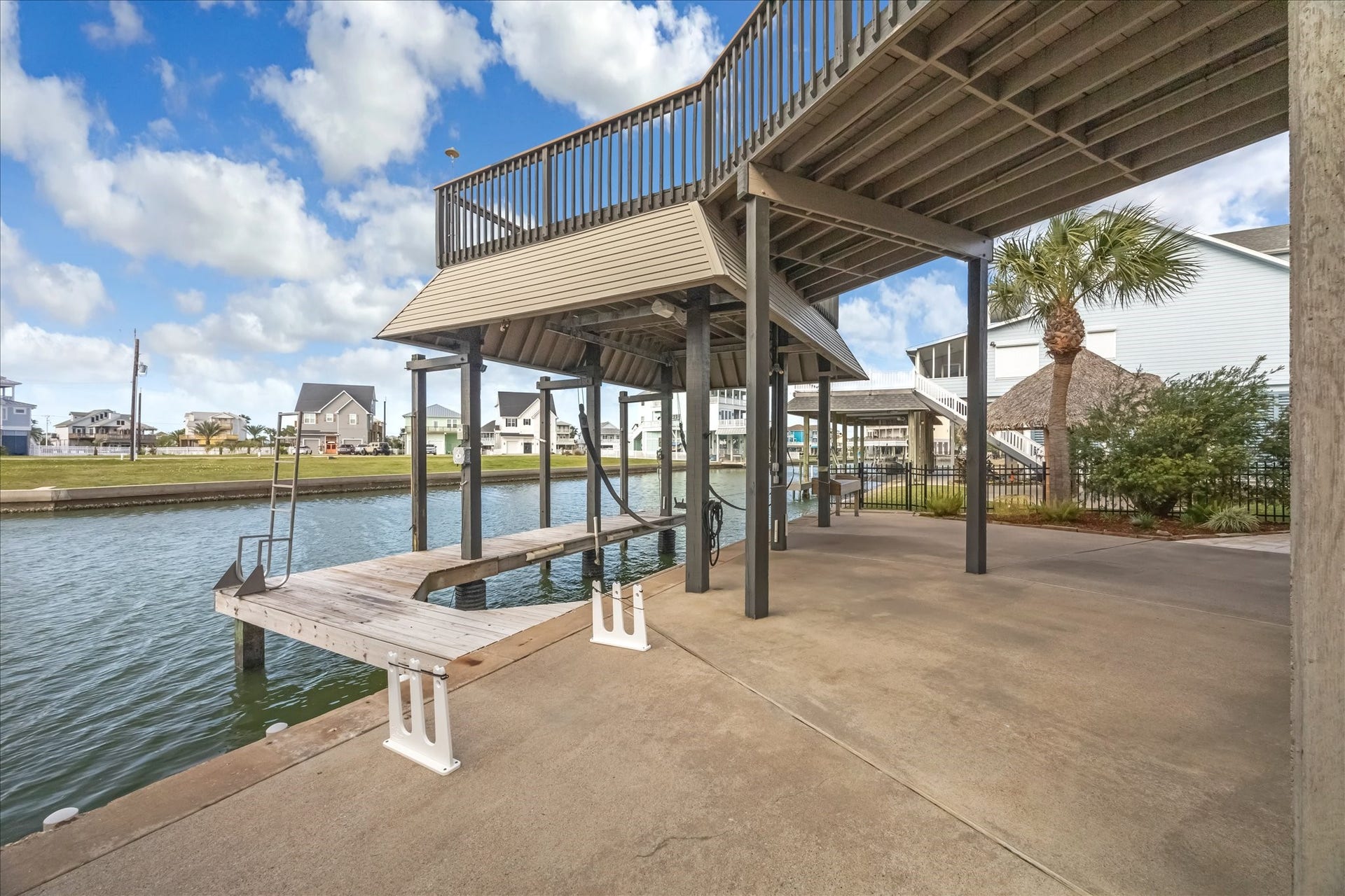 519 Westerly Drive, Tiki Island, TX 77554 With your own private dock and boat lift, you have direct canal access. The area is well-maintained, with a spacious concrete patio, palm tree, and a view of neighboring homes, perfect for boating enthusiasts.