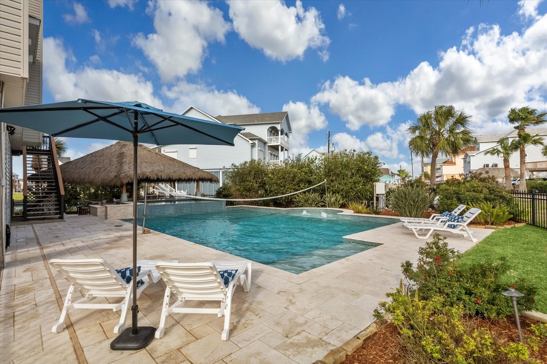 519 Westerly Drive, Tiki Island, TX 77554 Beautiful spacious pool with palapa and a swimup bar. Lush greenery, and palm trees, creating a relaxing outdoor oasis. Ideal for entertaining or enjoying a tranquil retreat.