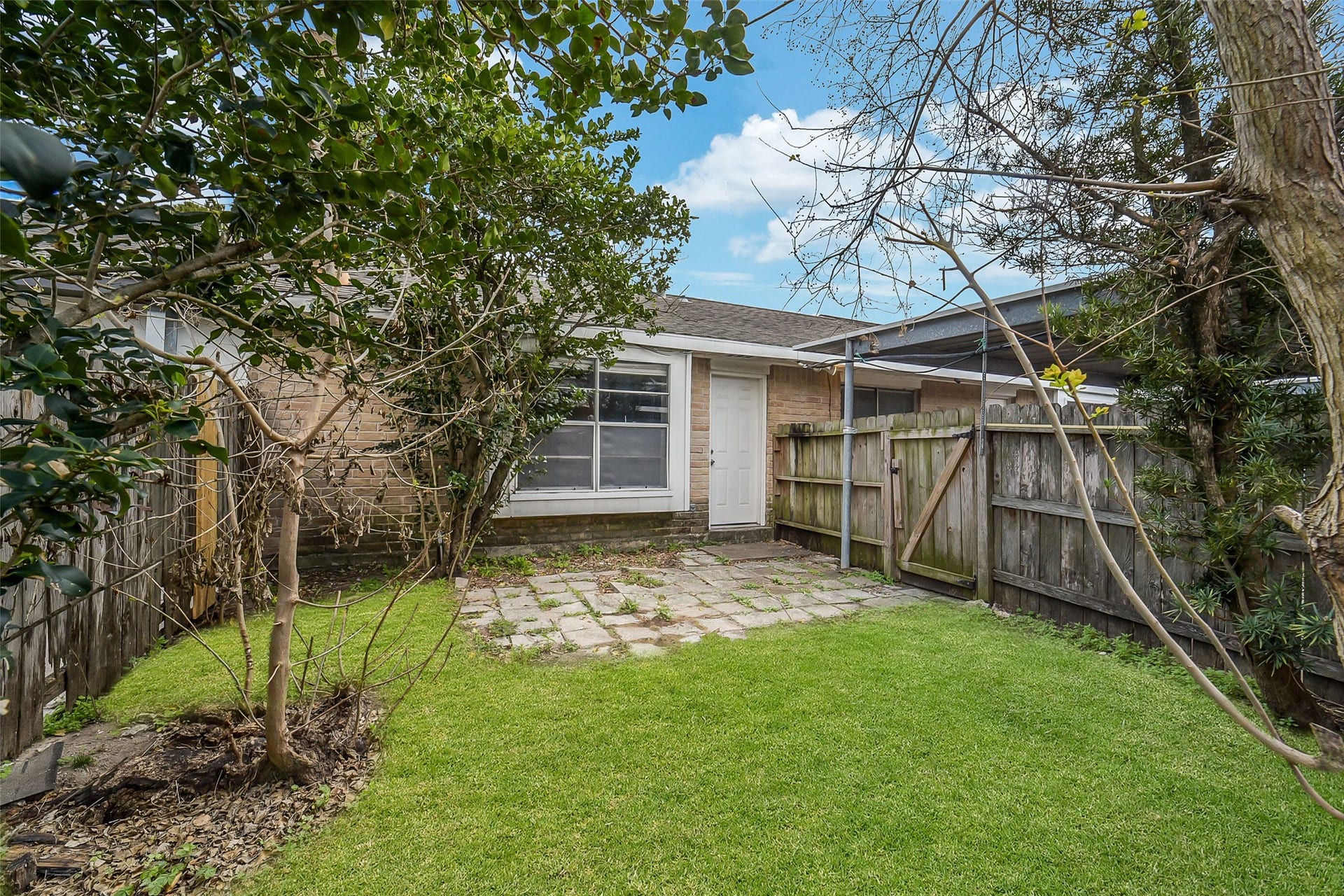 7265 Chasewood Drive, Houston, TX 77489 A second view highlights the backyard's generous green space, mature trees, and private patio, creating a peaceful setting for morning coffee, pets, gardening, or entertaining. The gated yard offers a comfortable outdoor retreat just beyond the back door.
