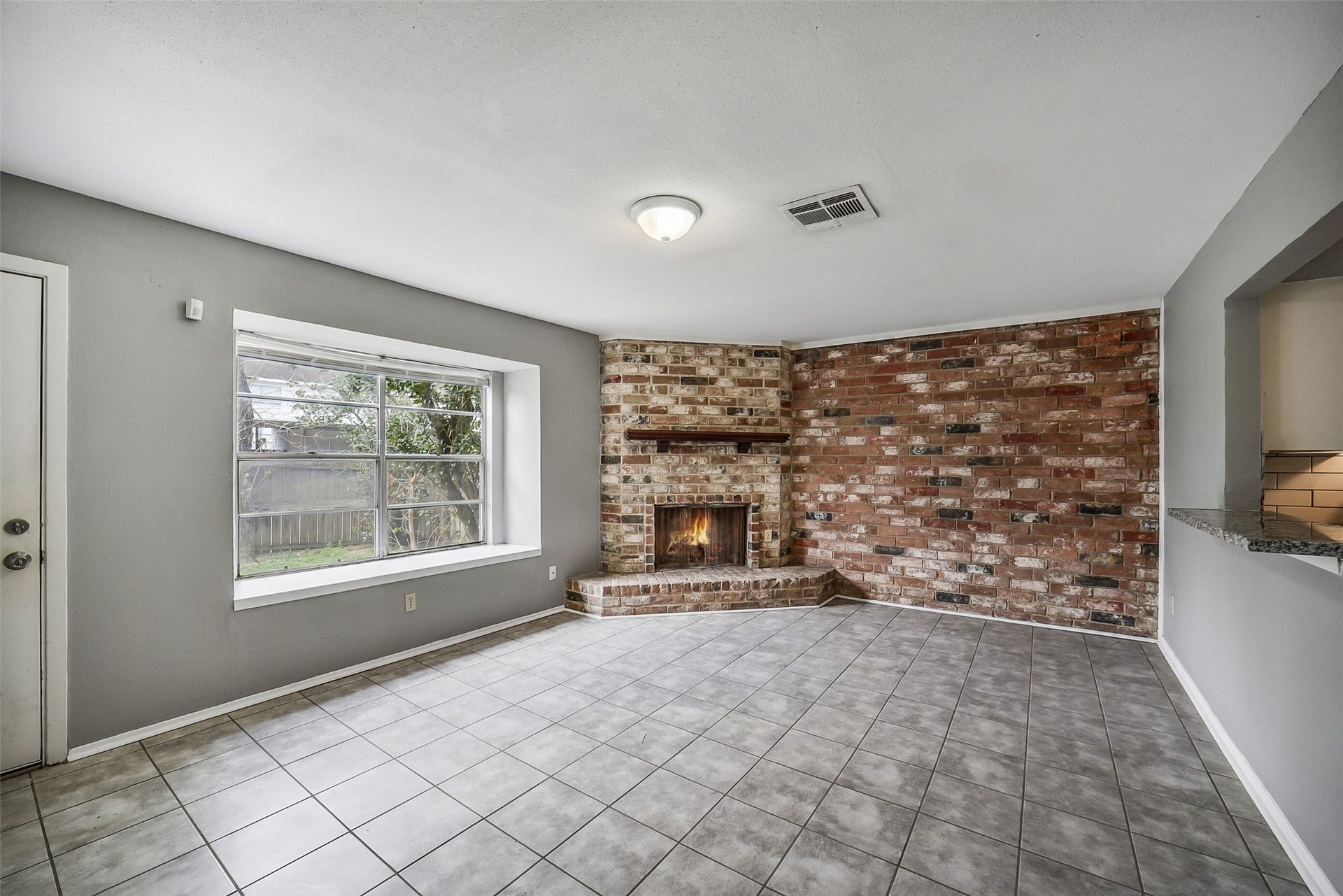 7265 Chasewood Drive, Houston, TX 77489 The spacious family room is filled with natural light and anchored by a striking floor-to-ceiling brick corner fireplace with raised hearth and mantel. Durable tile flooring, neutral finishes, and an open layout create a comfortable space for relaxing or gathering with family and friends.
