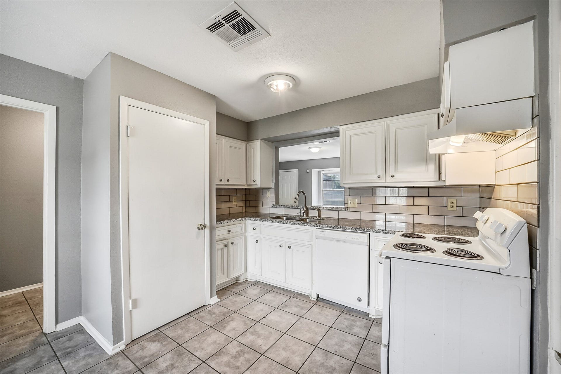 7265 Chasewood Drive, Houston, TX 77489 The updated kitchen features granite countertops, freshly painted white cabinetry, a classic subway tile backsplash, and abundant workspace for meal preparation. A large pass-through opening keeps you connected to the living area while adding an open, airy feel.