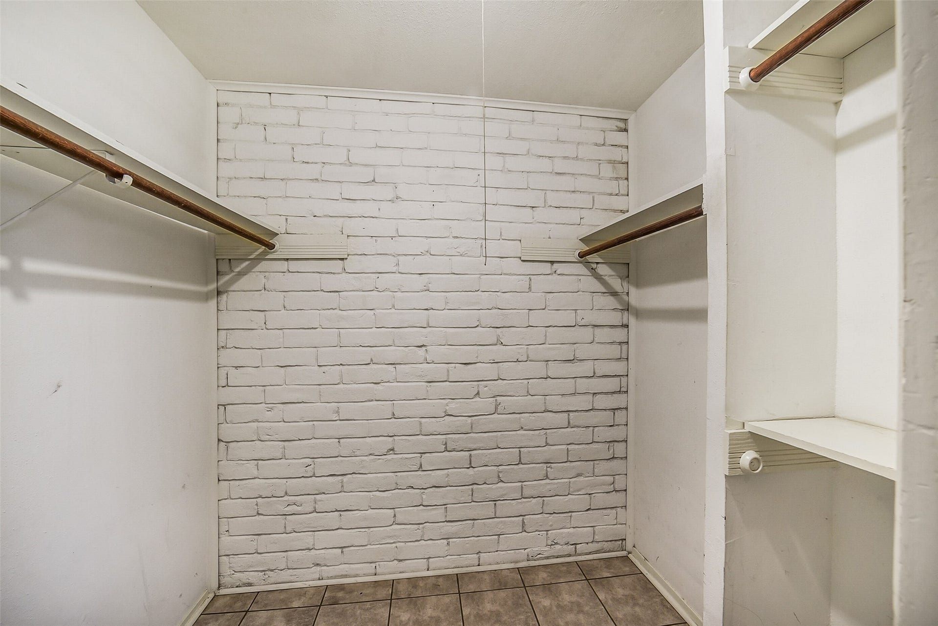 7265 Chasewood Drive, Houston, TX 77489 The spacious walk-in closet offers generous hanging space, built-in shelving, and a unique painted brick accent wall that adds a touch of character. Plenty of room keeps clothing, shoes, and seasonal items neatly organized and easily accessible.