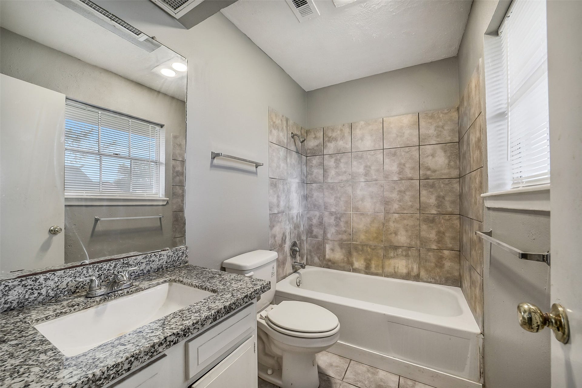 7265 Chasewood Drive, Houston, TX 77489 The private ensuite bath features an updated granite vanity, painted cabinetry, and a tub/shower combination with an oversized tile surround extending to the ceiling. A large window provides abundant natural light, creating a bright, fresh space to begin and end your day.