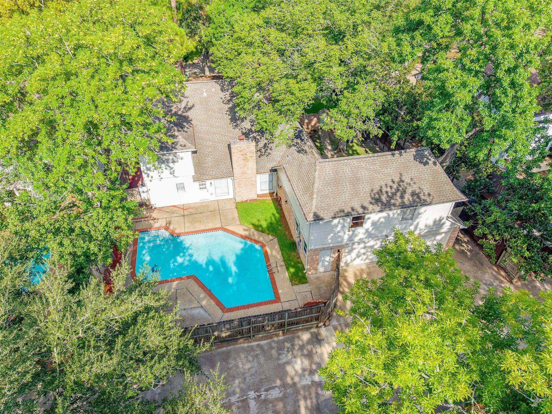 Charming home with a private backyard oasis featuring a sparkling pool surrounded by lush trees, offering a perfect retreat for relaxation and entertainment.