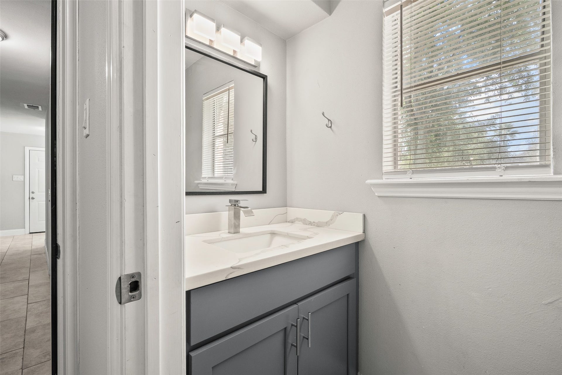 Stylish bathroom with a modern vanity, sleek faucet, and a large window for natural light.