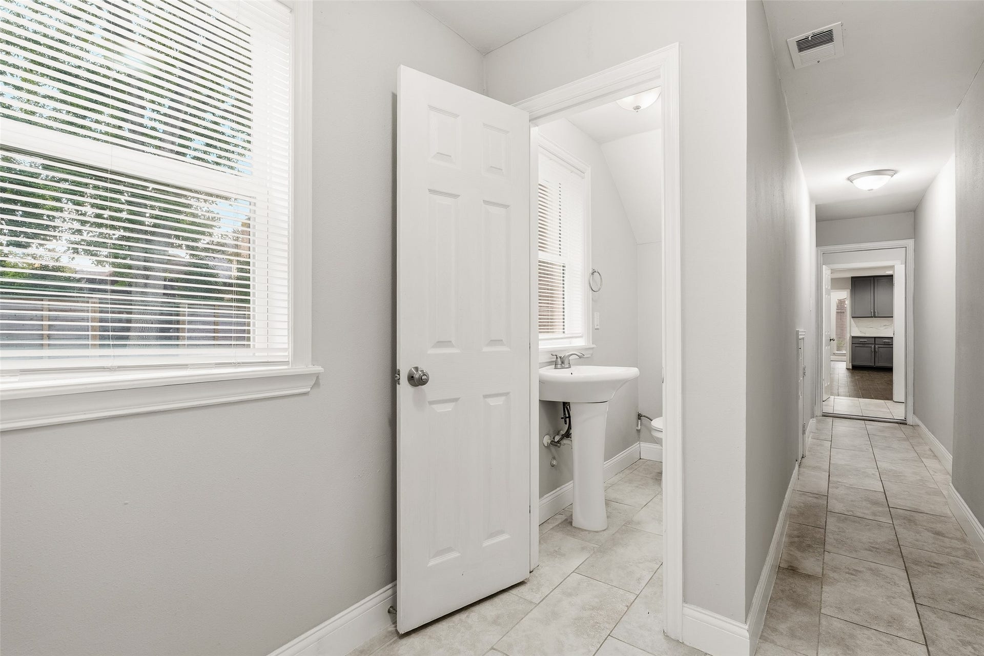 Bright hallway with a half bath, featuring a pedestal sink and window for natural light.