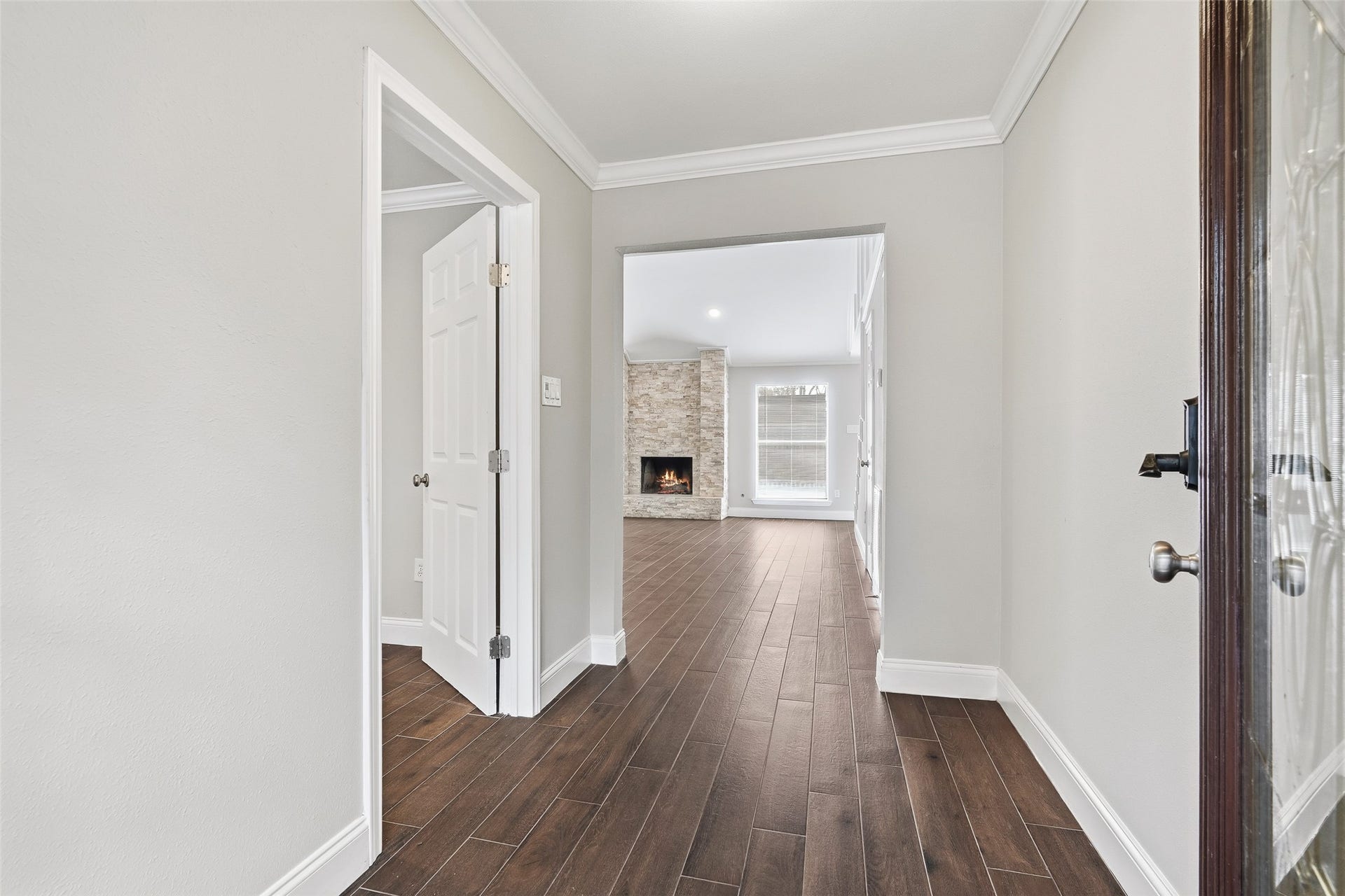 Step into a welcoming entryway leading to a spacious living area featuring a cozy stone fireplace and abundant natural light.