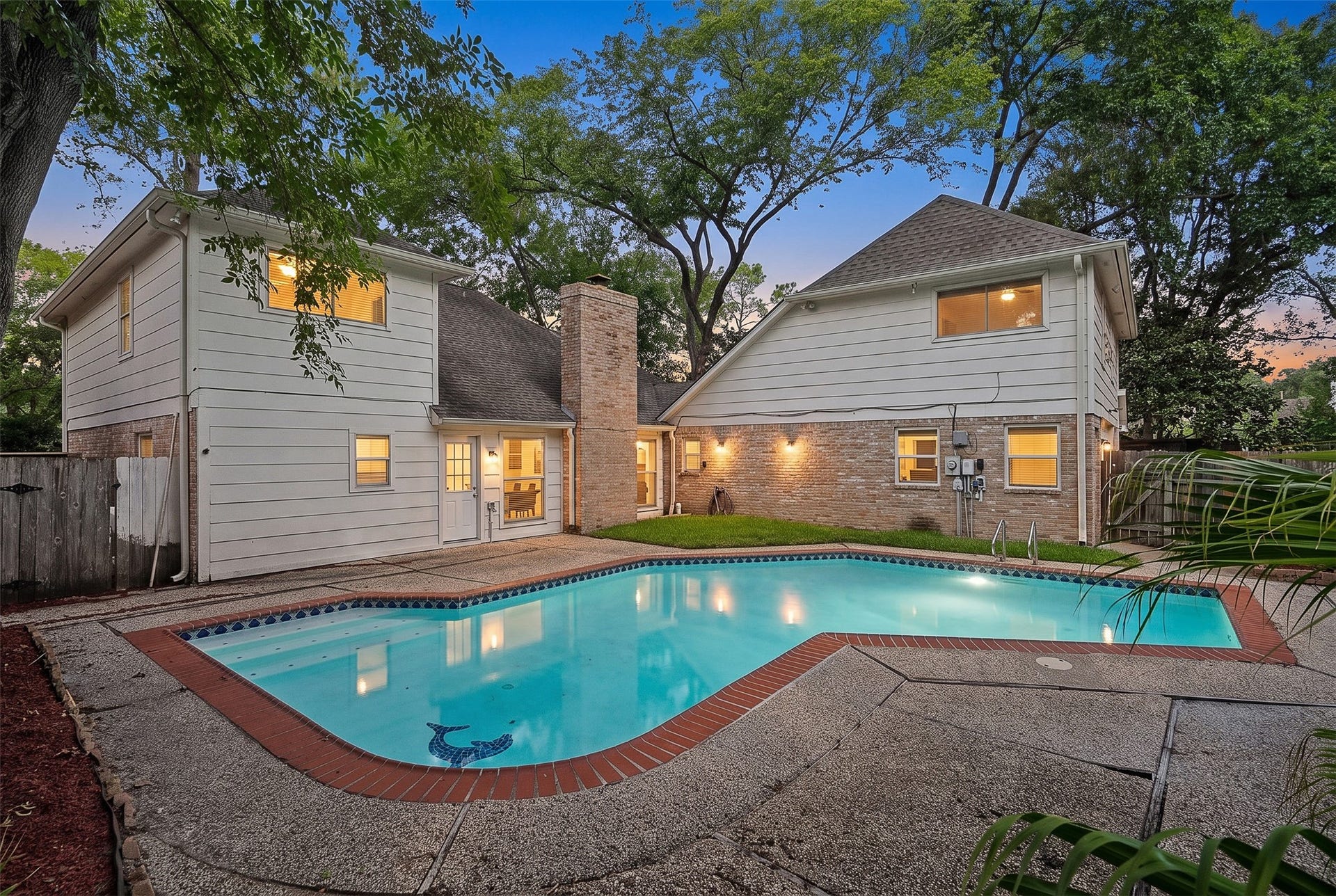 Charming two-story home with a spacious backyard featuring a sparkling pool, surrounded by lush greenery and ample patio space for relaxation and entertaining.