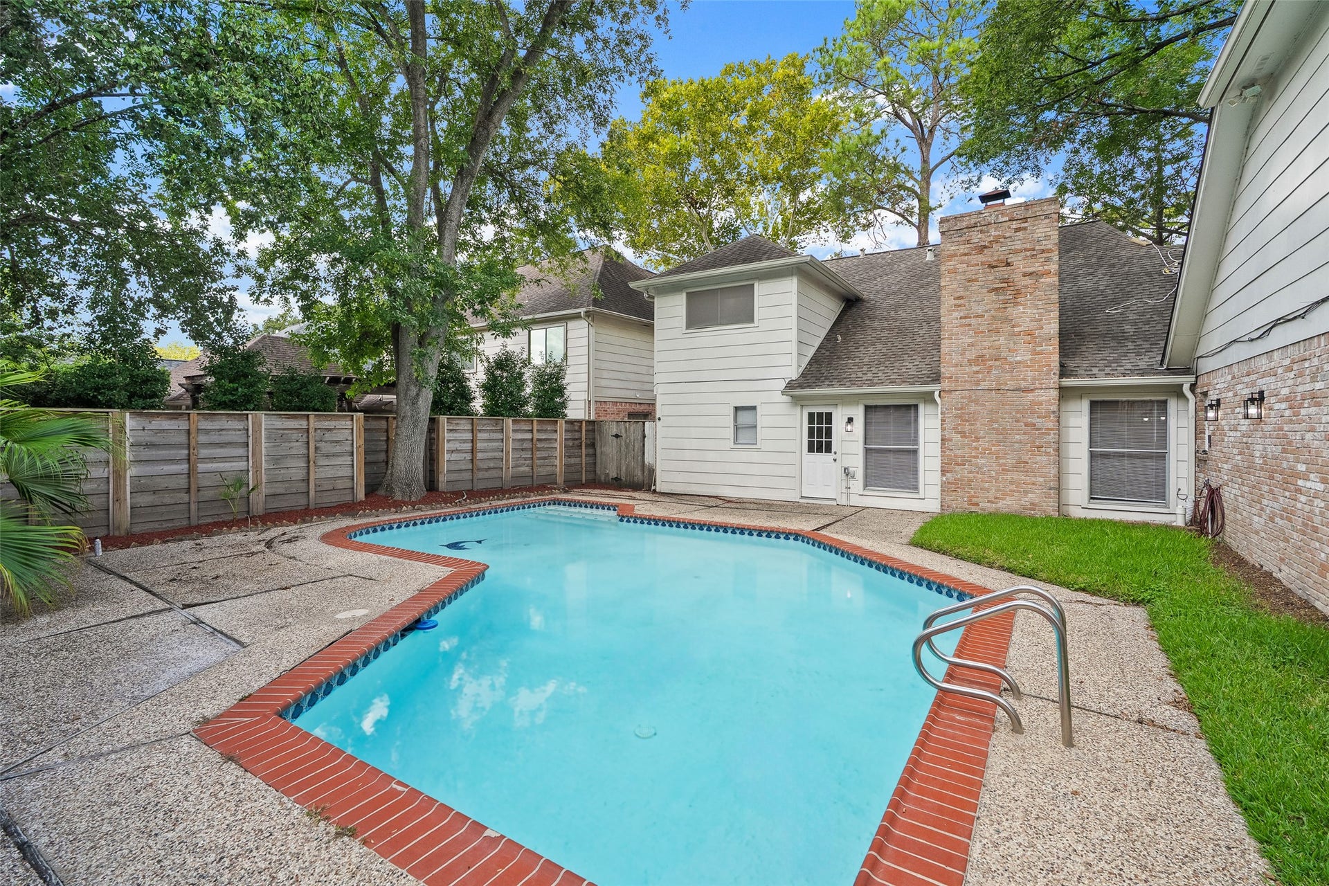 Experience serene outdoor living with this charming backyard, featuring a sparkling swimming pool and a cozy patio space perfect for relaxation or entertaining.