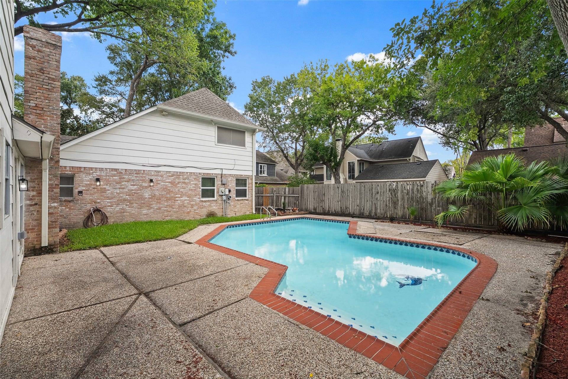 Enjoy a private backyard oasis featuring a sparkling pool surrounded by lush greenery and a spacious patio, perfect for relaxation and entertainment.