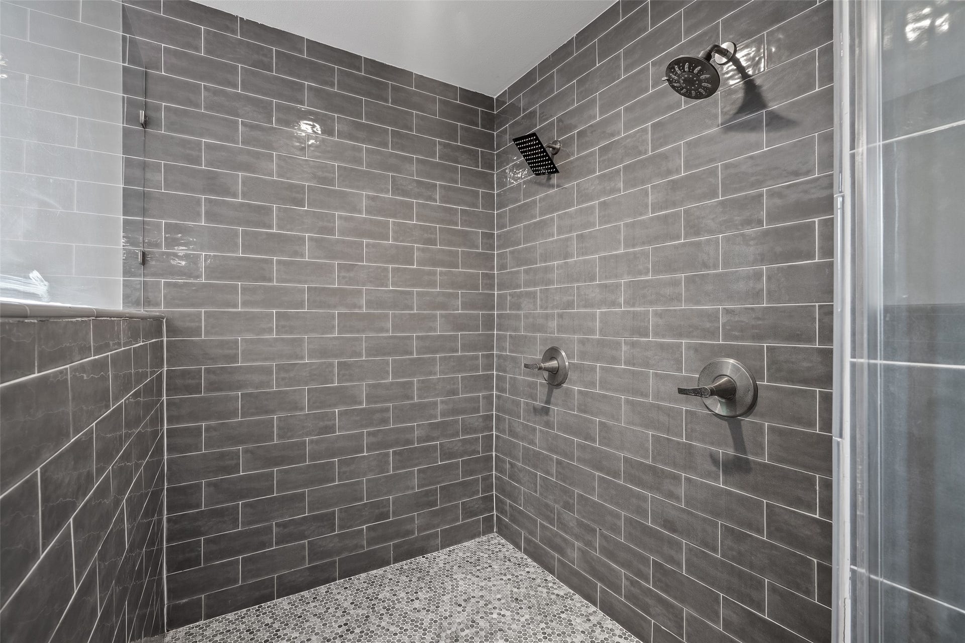 Luxurious shower featuring sleek gray subway tiles and dual showerheads for a spa-like experience.