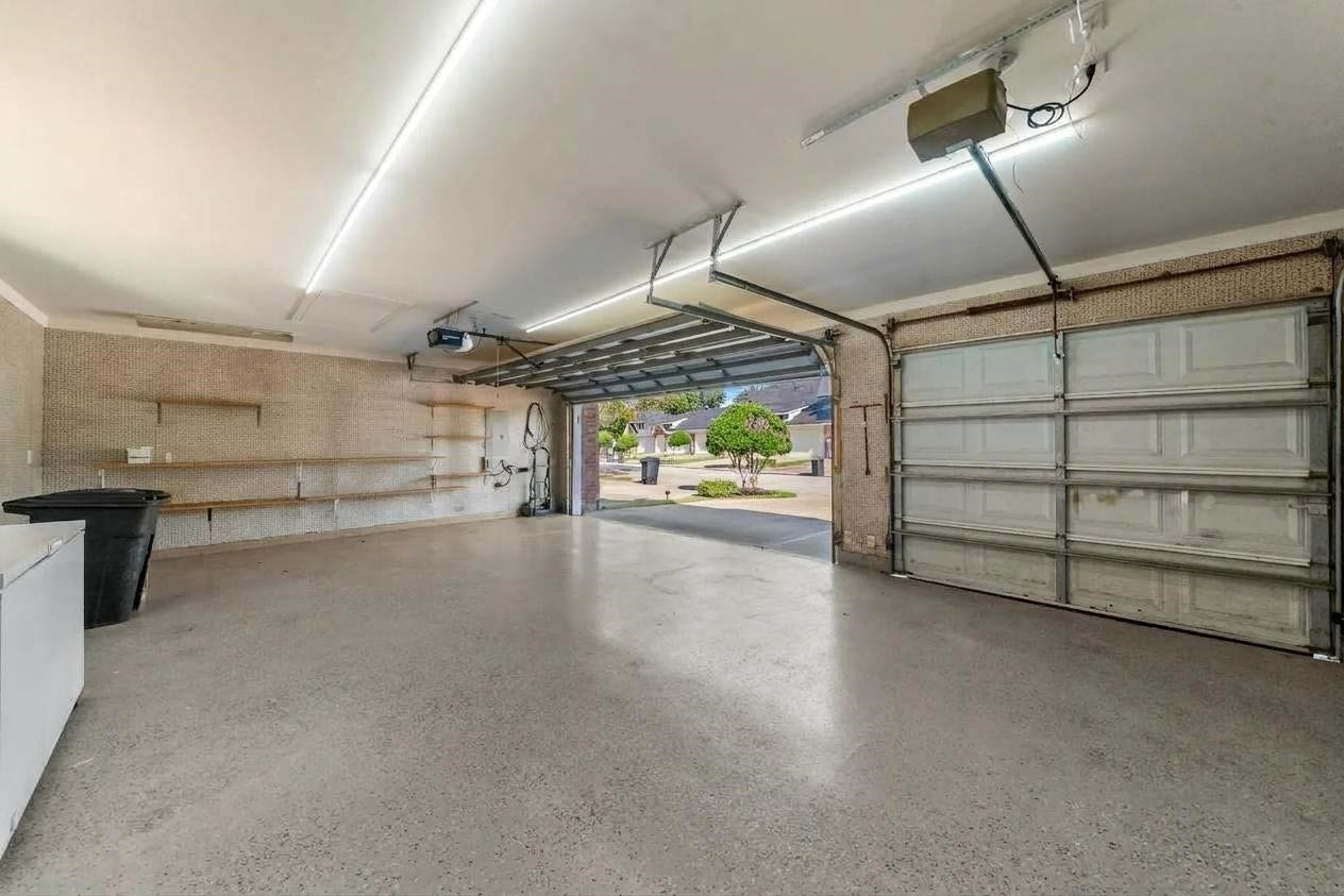 Oversized three car garage.  Walls are covered in corkboard, with shelving, and cabinets (not shown).  This garage is ready for your power tools and projects.