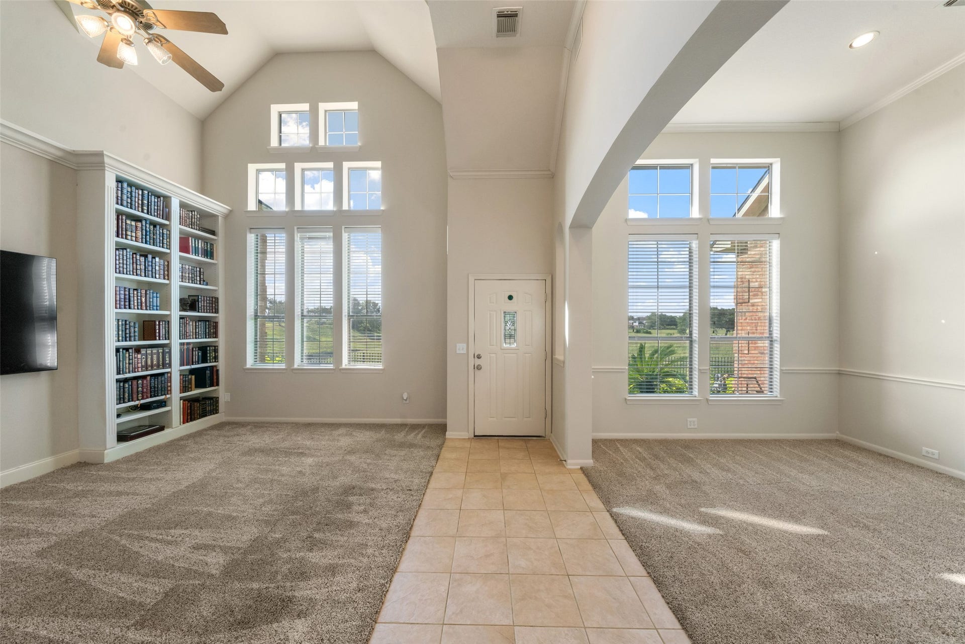 Soaring high ceilings with floor to ceiling windows allows for unobstructed views of the golf course.  Open concept living room, entry, and dining room.