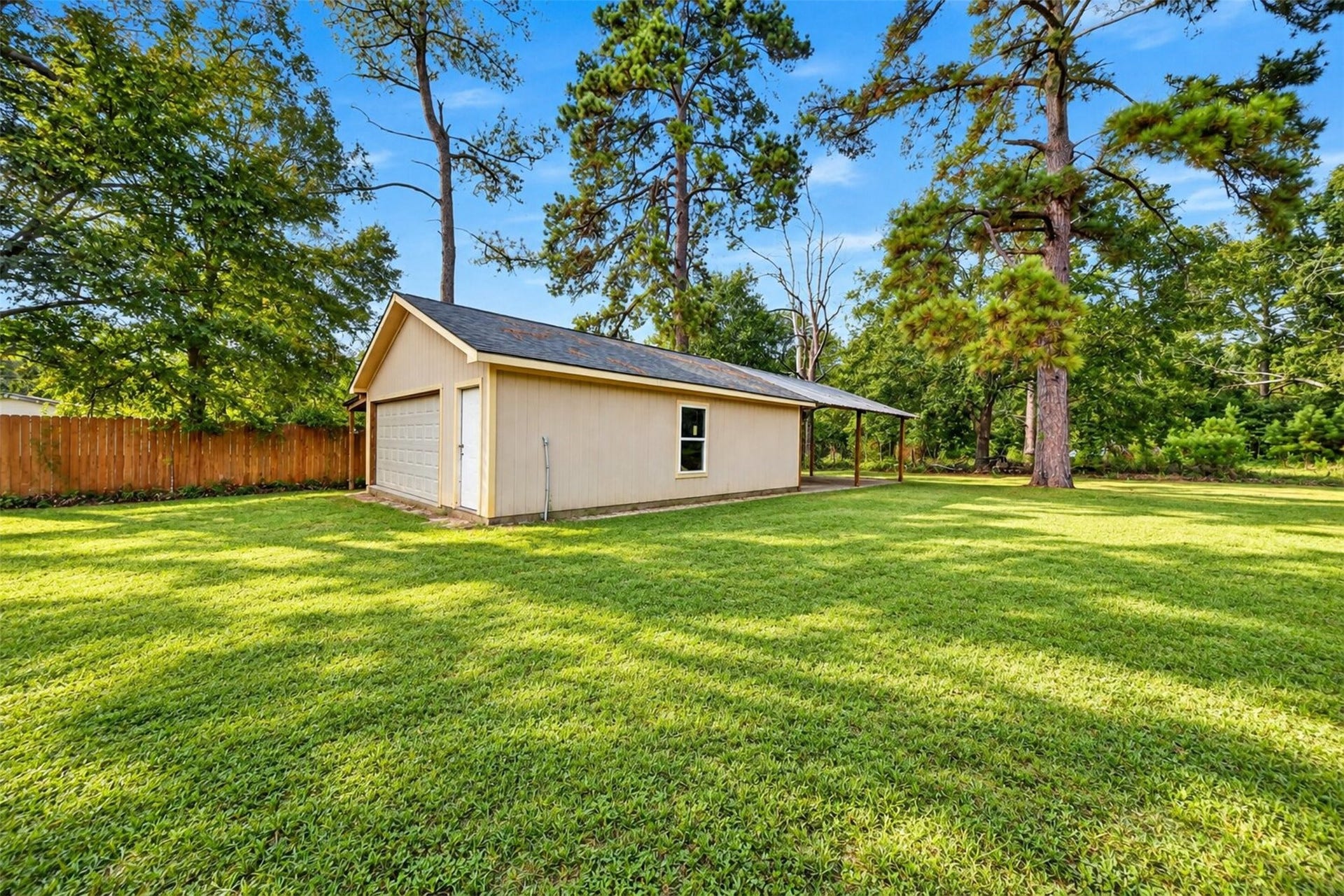 2581 Mann Road, Conroe, TX 77303 Spacious backyard with mature trees, open green space, and a detached storage building.