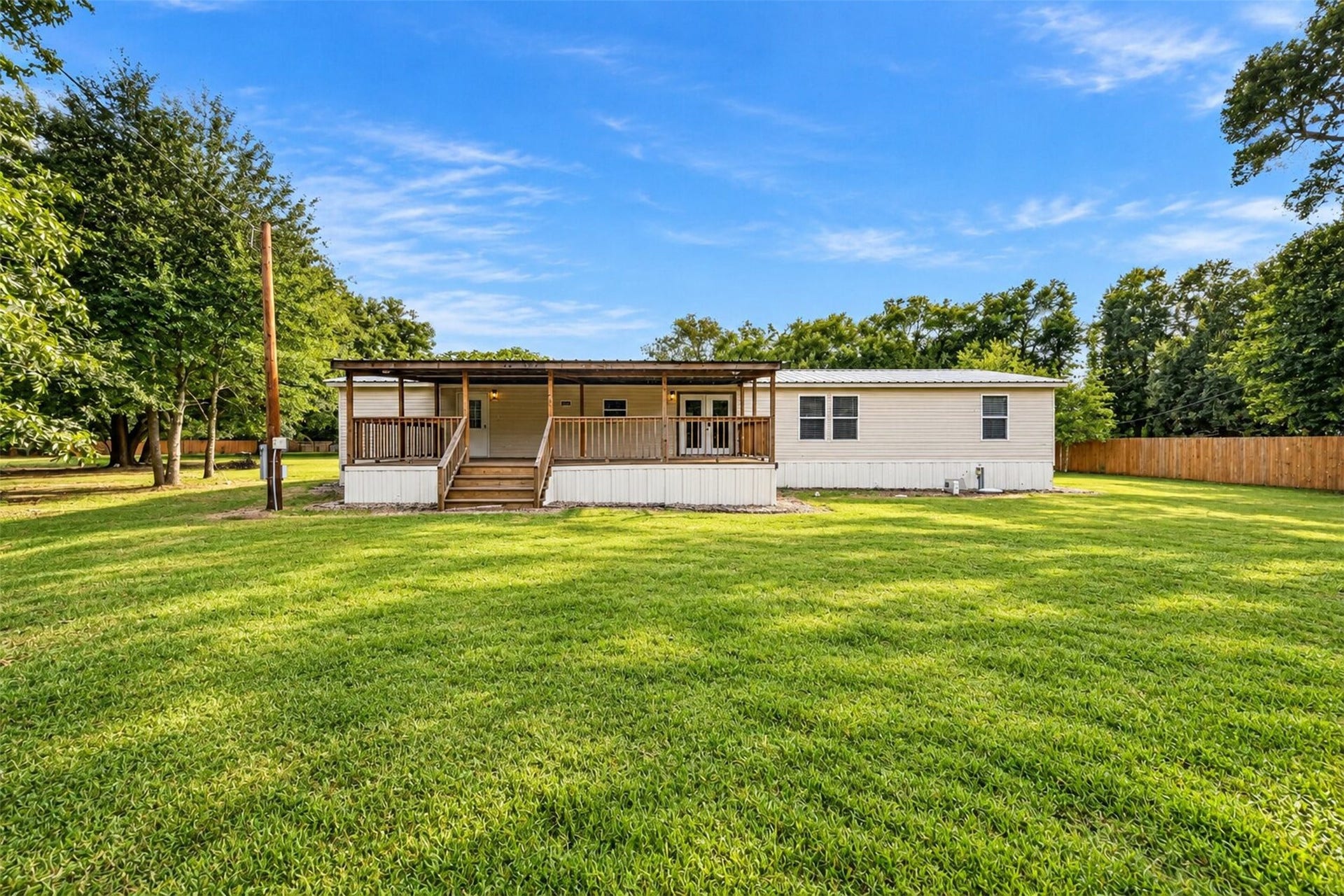 2581 Mann Road, Conroe, TX 77303 Wide exterior view highlighting the expansive lawn and peaceful, tree lined setting.